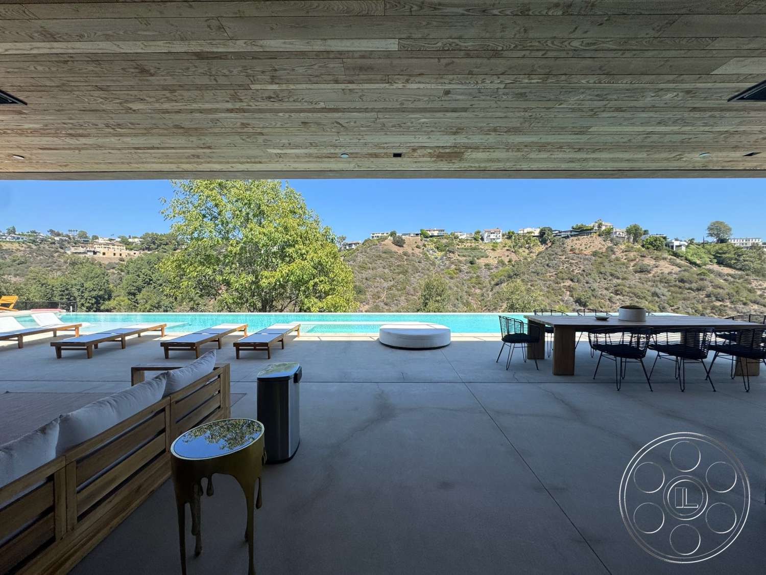 Modern 527 - exterior, wood panel ceiling, glass sliding doors, wooden dining table, modern outdoor furniture, lounge chairs, infinity pool, built-in seating, rectangular pool, natural landscape view, concrete patio flooring, outdoor kitchen space, metal wire chairs