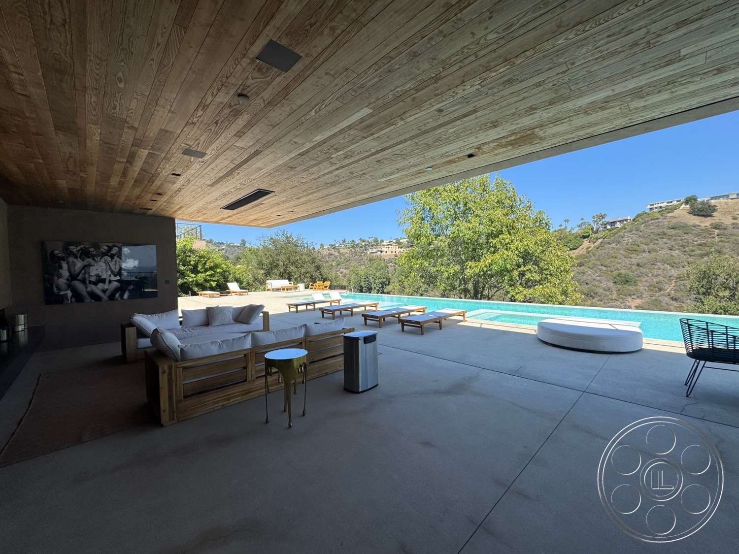 Modern 527 - exterior, open floor plan, natural wood accents, minimalist design elements, infinity pool, rectangular pool, concrete patio flooring, stone fireplace wall, modern outdoor seating area, urban hillside setting, wood lounge chairs, wood slatted ceiling, glass wall opening to outdoor space, contemporary landscape view