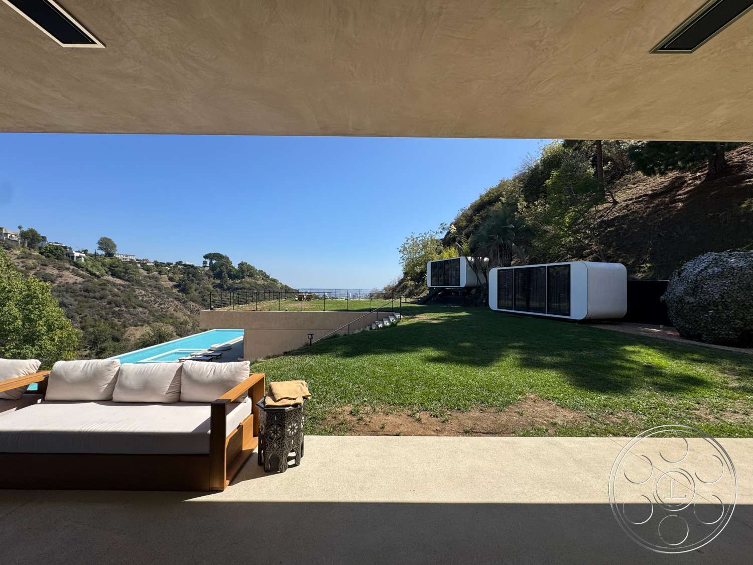 Modern 527 - infinity pool, open-air living space, modern outdoor seating, minimalist architectural design, natural grass lawn, concrete patio floor, exterior hillside location, glass pool edge, view of ocean landscape, white modular structures, contemporary exterior style