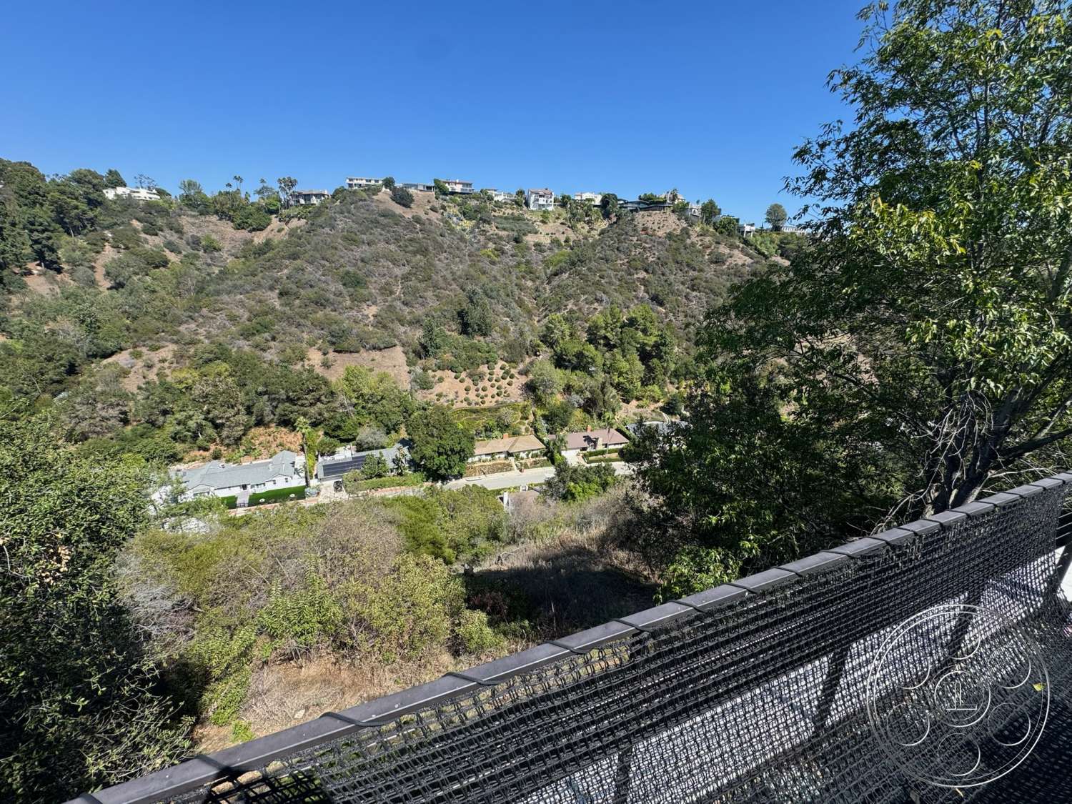 Modern 527 - exterior, modern architecture, flat roof, metal railing, concrete patio, landscaped hillside, urban residential area, hillside location, sunny day, view of surrounding greenery, tree-lined neighborhood, open views, terraced landscape