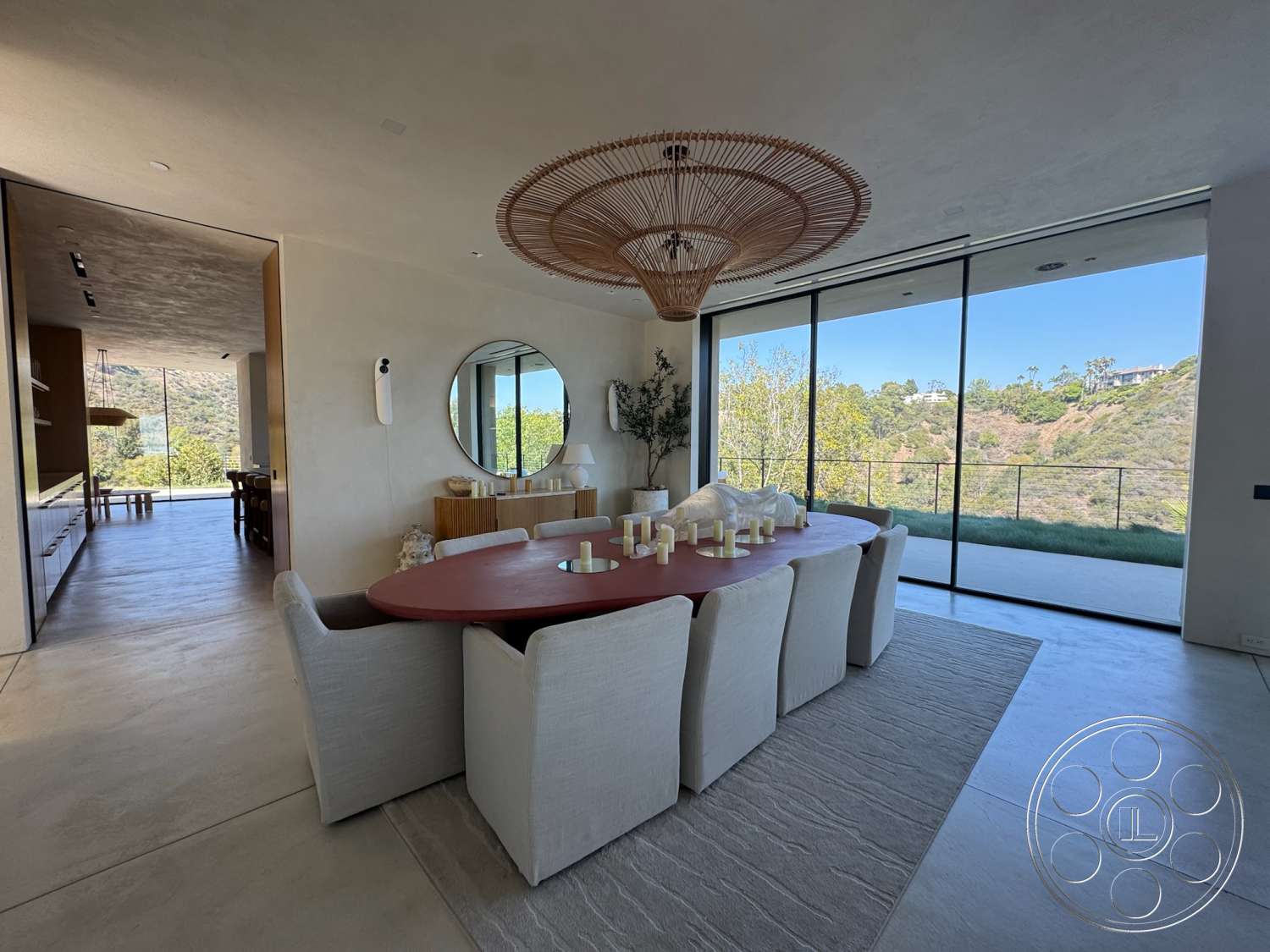 Modern 527 - modern decor, minimalist design, large glass sliding doors, greenery accents, concrete flooring, upholstered dining chairs, wooden sideboard, plaster walls, soft area rug, mountain view, rounded dining table, rattan pendant light fixture, mirror wall accent