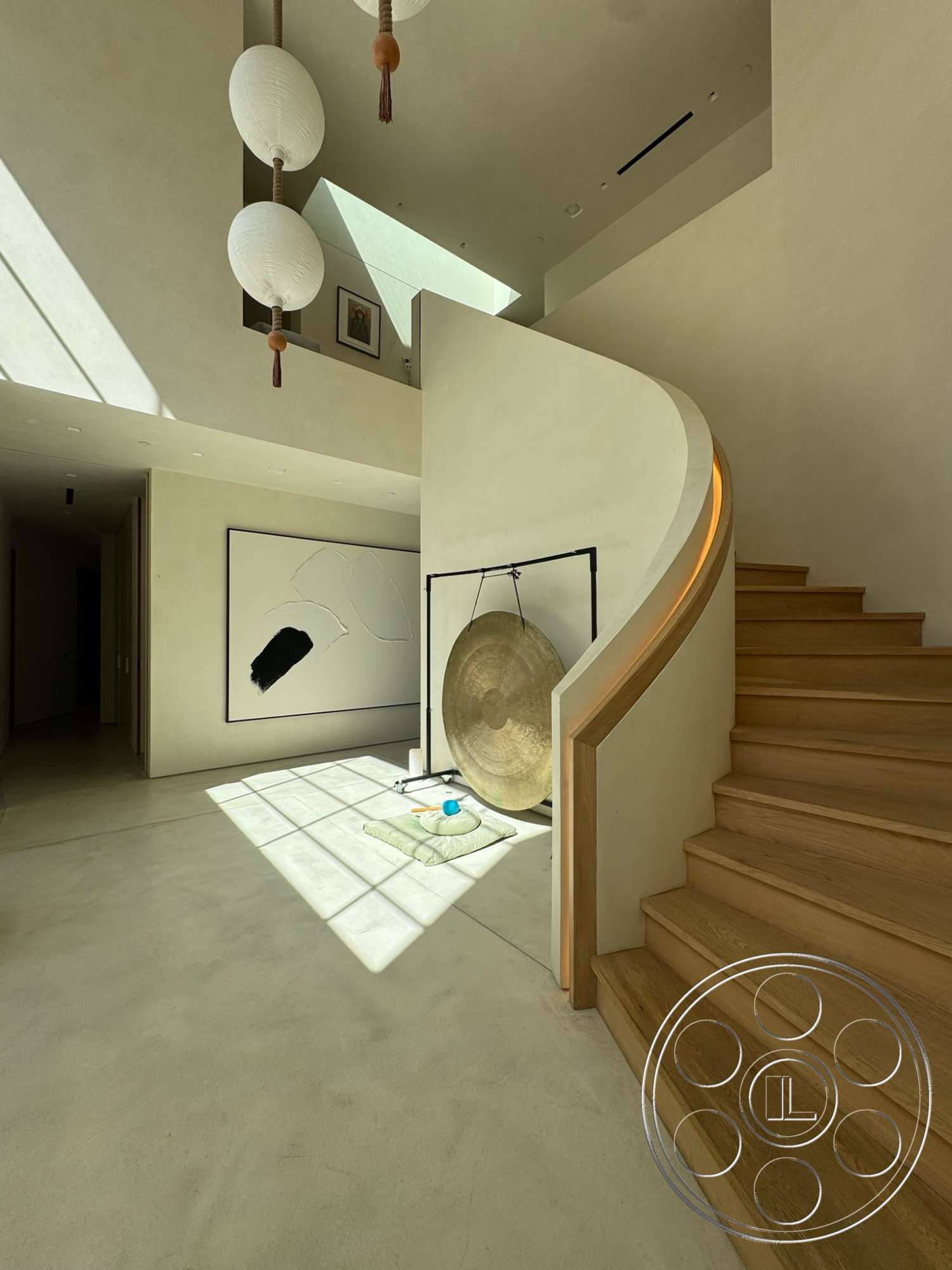 Modern 527 - neutral color palette, natural light, concrete floor, modern pendant lighting, high ceiling, floor-to-ceiling windows, plaster wall finish, wooden stair treads, curved staircase, minimalist artwork, open entrance hall, hand-crafted gong, light wood handrail