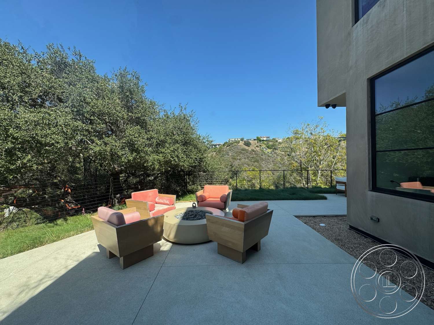 Modern 527 - exterior, surrounding trees, hilltop view, fire pit area, modern outdoor seating, concrete patio flooring, rectangular patio, landscaped grassy area, metal wire fence