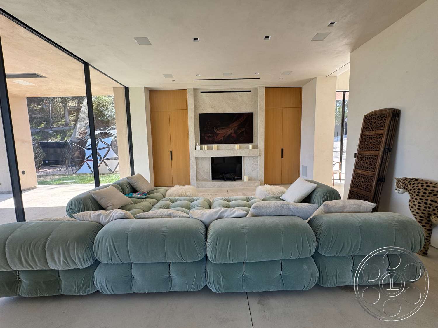 Modern 527 - open floor plan, concrete flooring, minimalist design elements, floor-to-ceiling windows, textured plaster walls, cozy living room, exposed ceiling lights, marble fireplace surround, velvet sectional sofa, natural wood cabinet doors, modern artwork wall