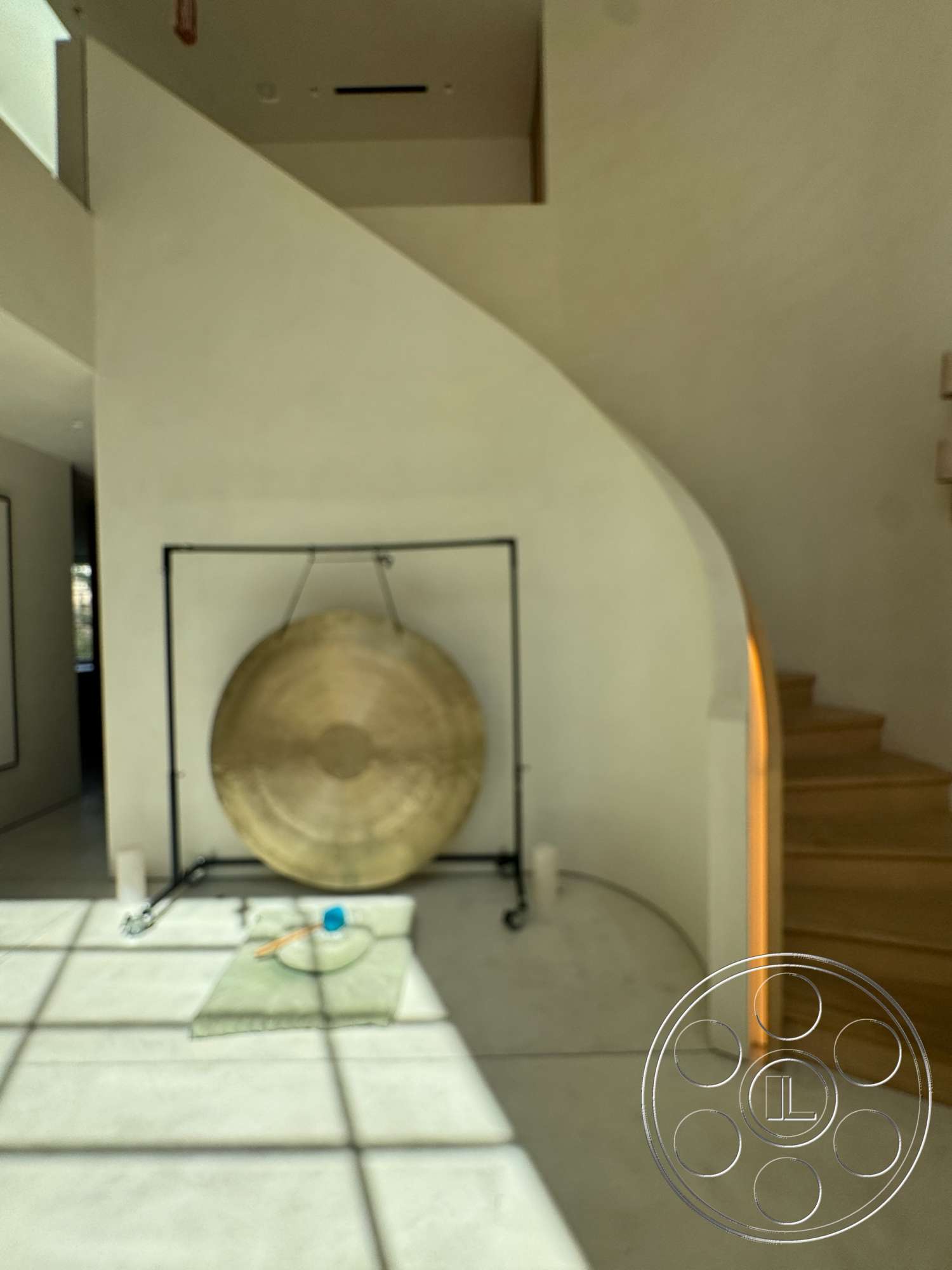 Modern 527 - large windows, minimalist design, natural lighting, concrete flooring, interior space, plastered walls, wooden stair treads, curved staircase, warm wood accents, guitar-shaped gong hanging