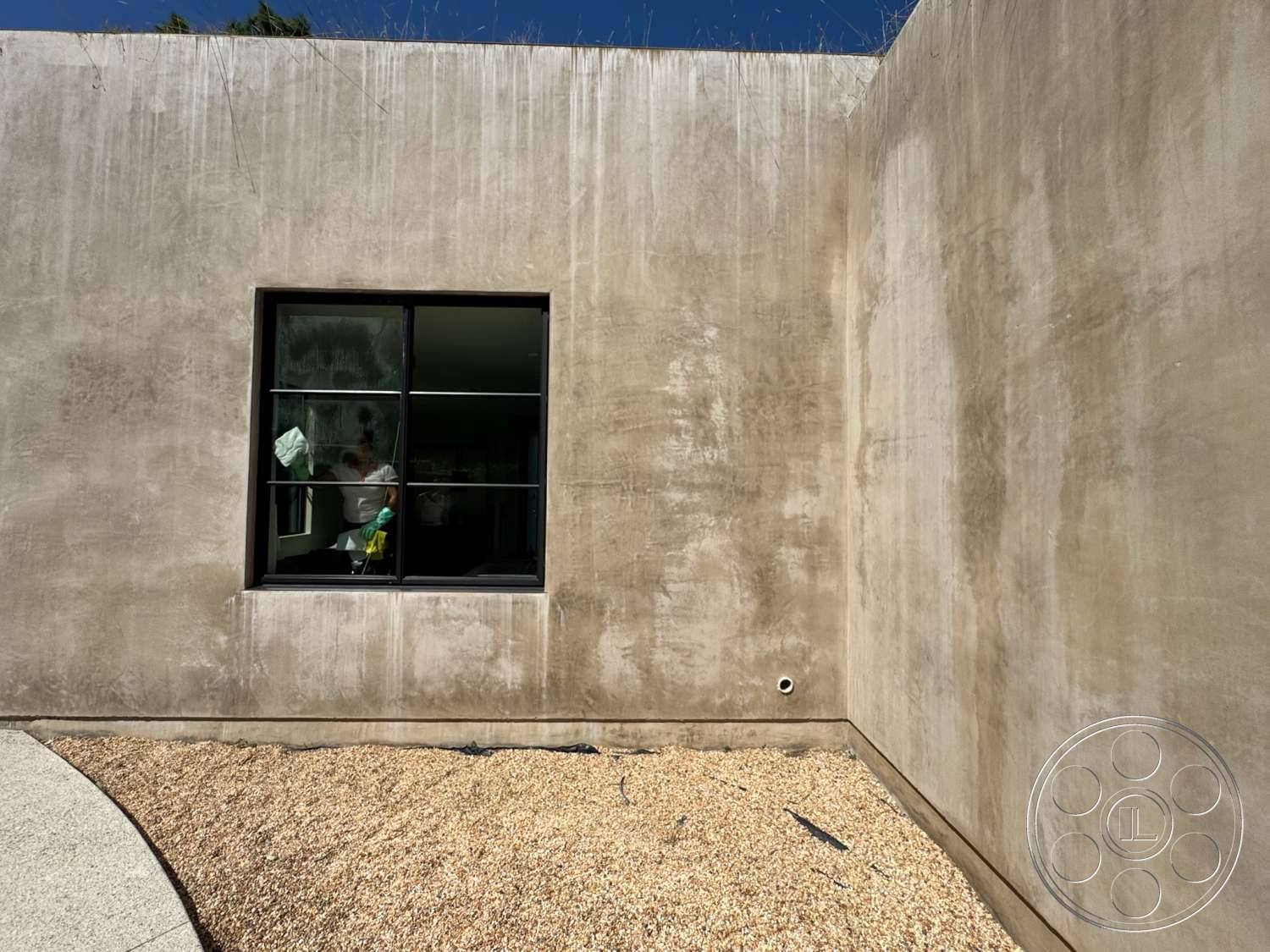 Modern 527 - exterior, open floor plan, gravel landscaping, textured plaster walls, curved concrete pathway, minimalist architectural style, natural light emphasis, large black framed window