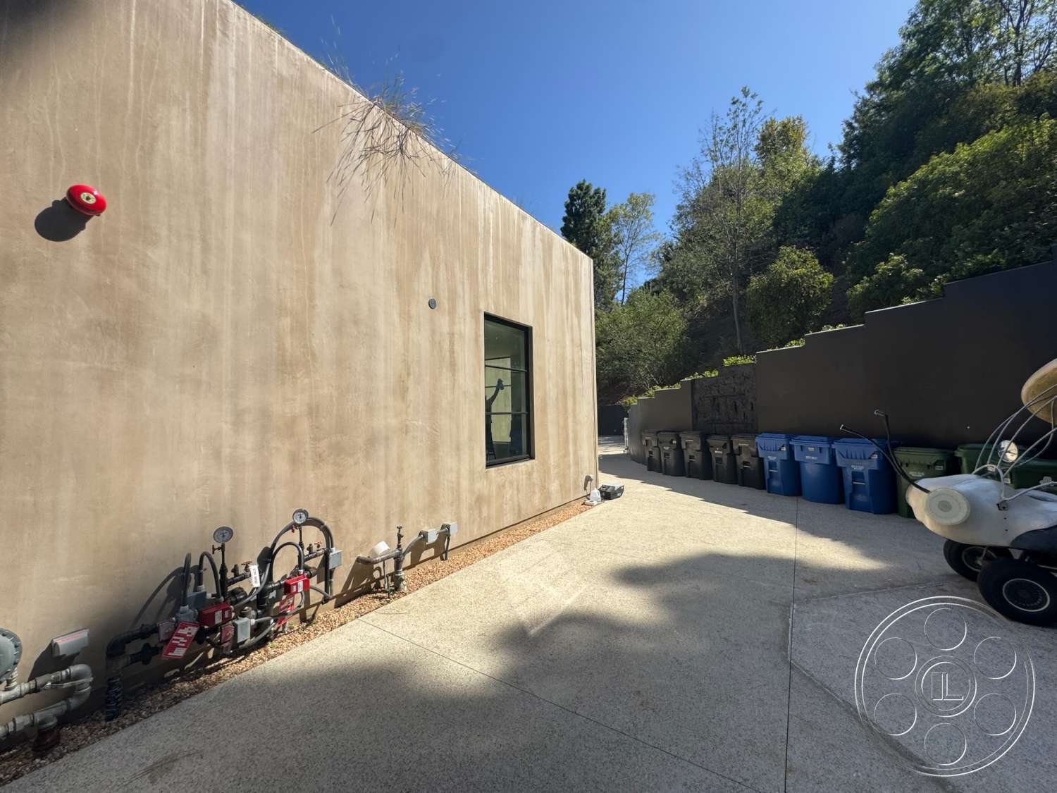 Modern 527 - exterior, surrounding trees, gravel landscaping, smooth concrete walls, minimalist architectural style, rectangular window, green waste bins, light-colored concrete driveway, water meters and pipes