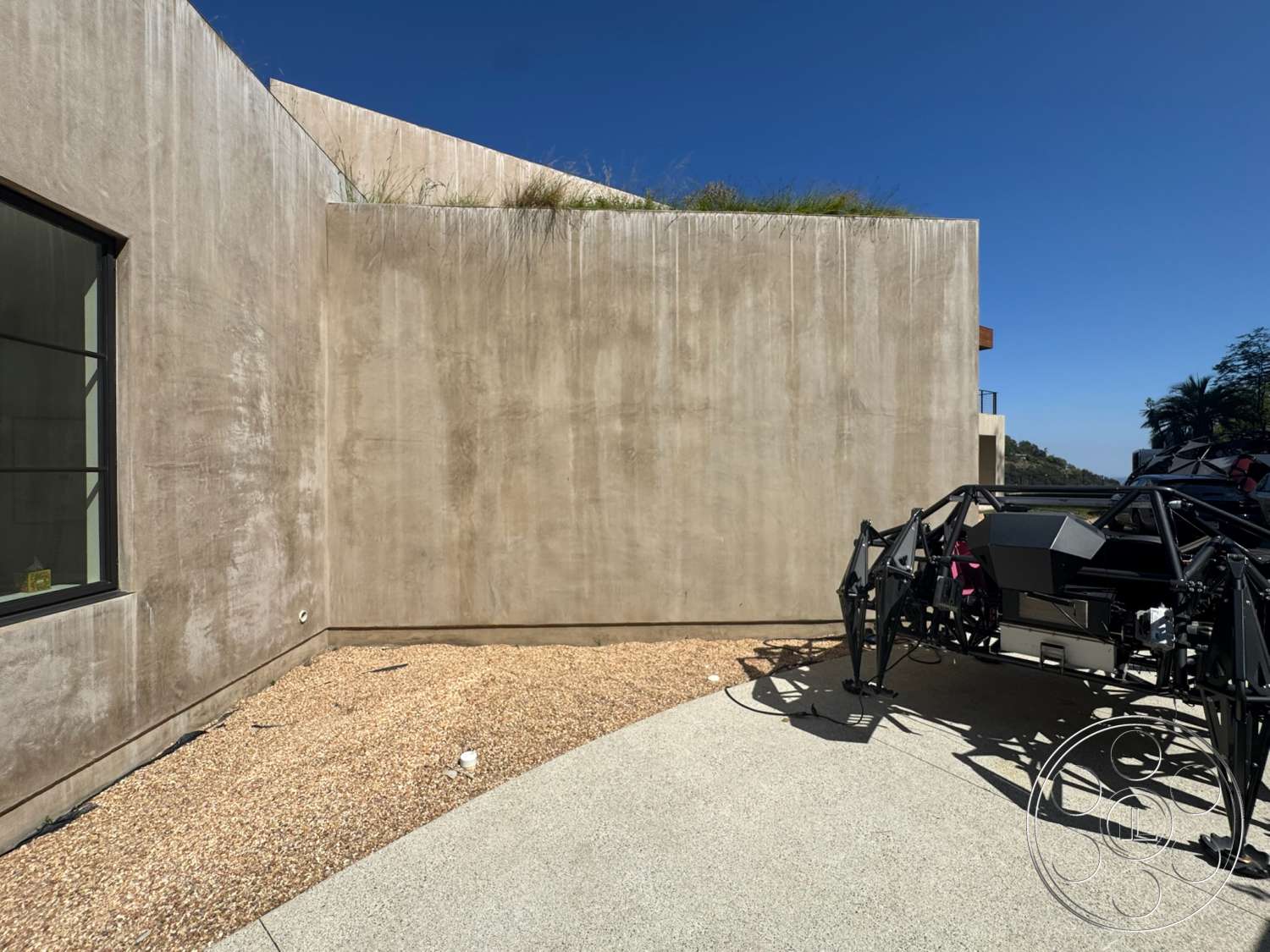 Modern 527 - exterior, minimalist design, landscaped area, floor-to-ceiling windows, outdoor sculpture, gravel ground cover, textured concrete facade, unpainted concrete walls, sloped roof with vegetation, geometric modern architecture