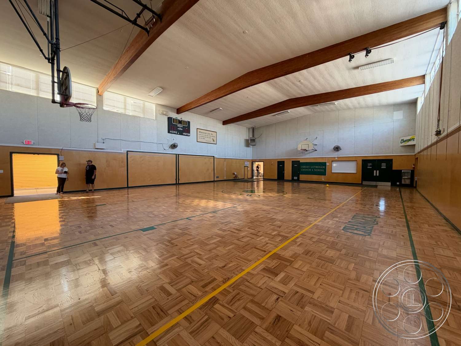 Community Center - floor-to-ceiling windows, basketball hoop, textured plaster walls, wood beam ceiling, parquet gymnasium flooring, orange vinyl wall panels, sports court interior, green painted wall accents, indoor athletic space