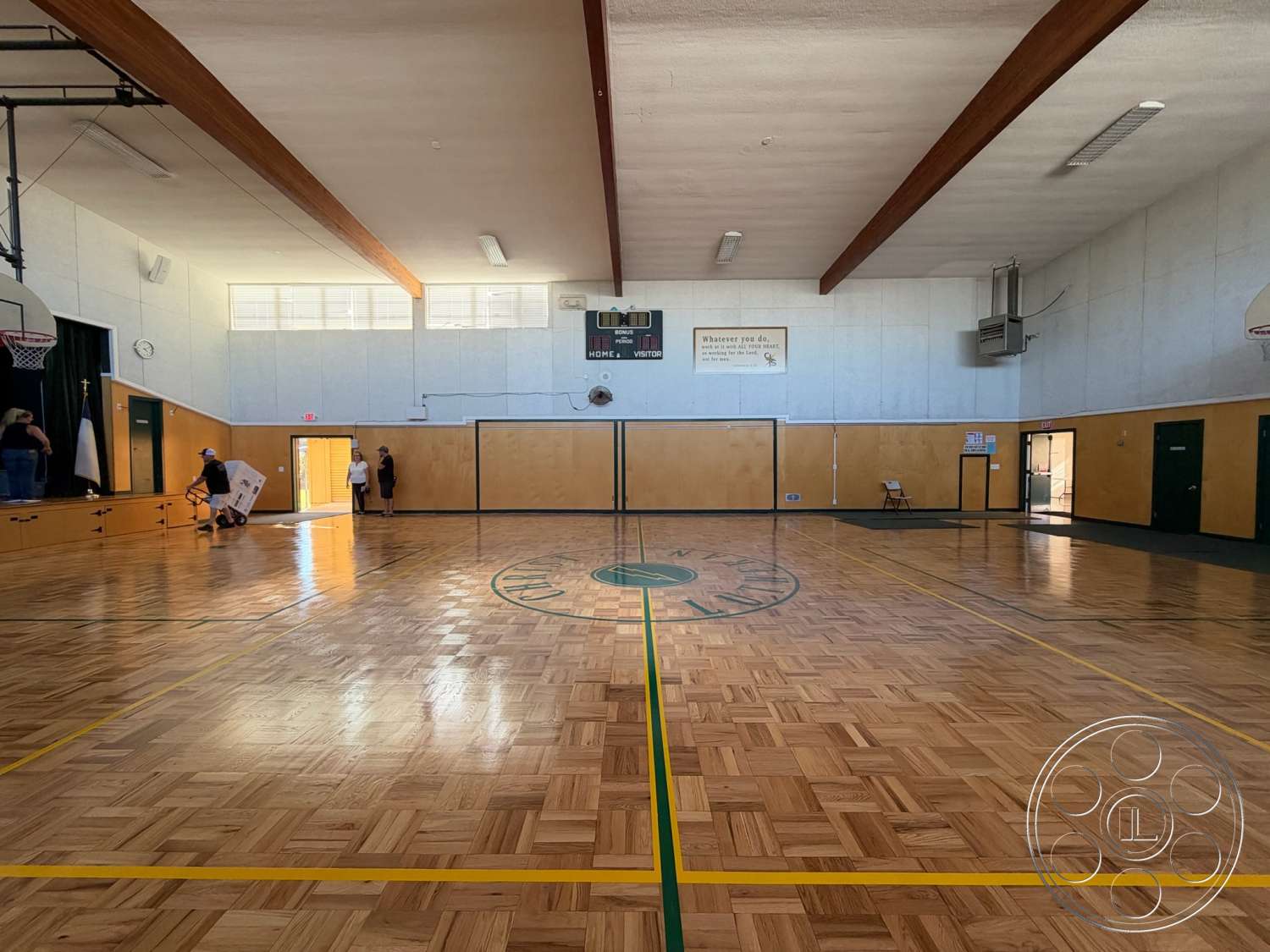 Community Center - exposed concrete walls, green accent wall, stage area, ventilation system, scoreboard, wood beam ceiling, ceiling-mounted lighting fixtures, glass block windows, basketball court markings, sports hall interior, parquet gym floor, yellow court lines, wooden bleachers