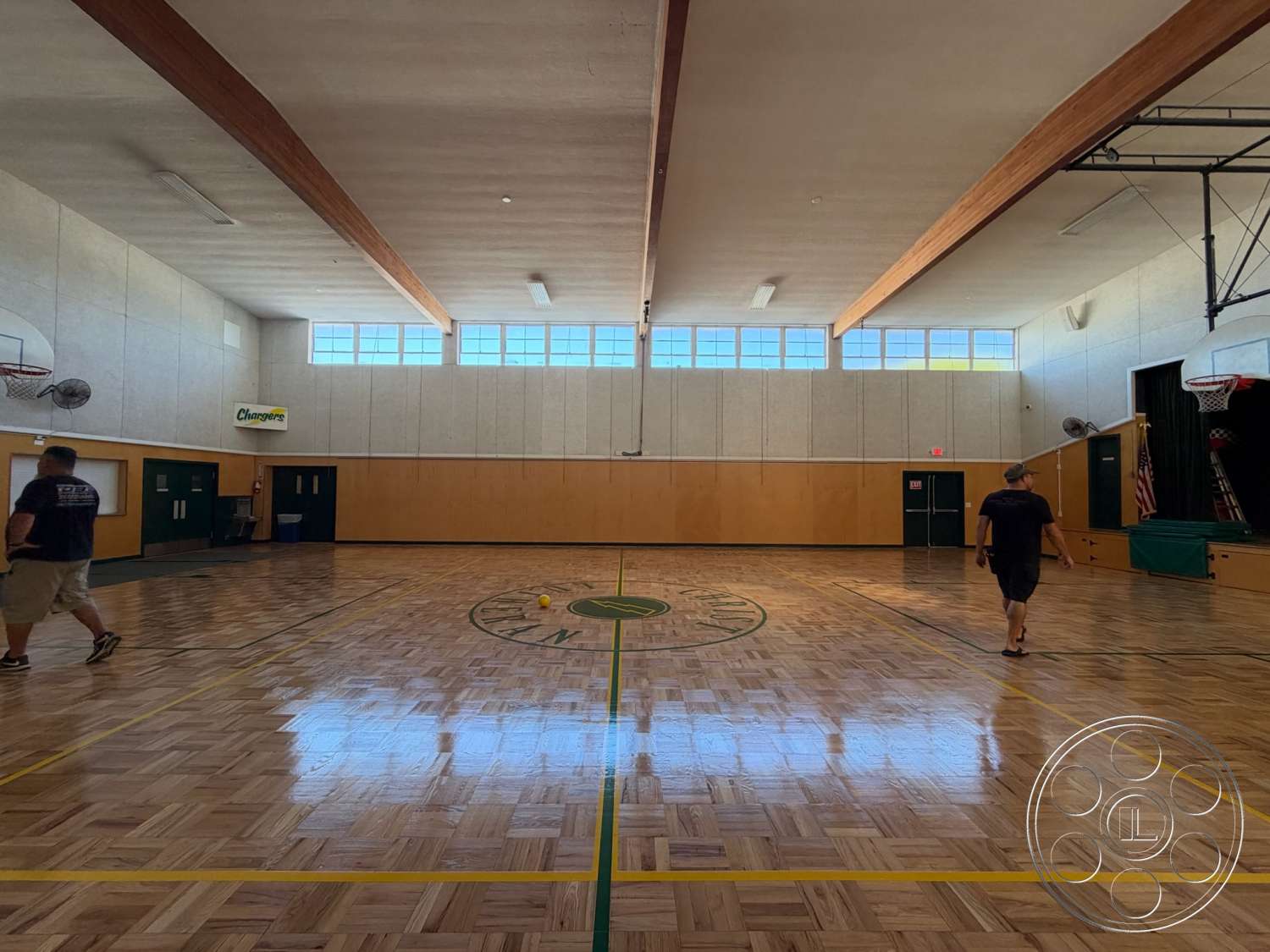 Community Center - floor-to-ceiling windows, green accent doors, wood beam ceiling, sports facility interior, panelled wood wall, hardwood gym flooring, basketball court layout, exposed HVAC ducts, light-colored drywall