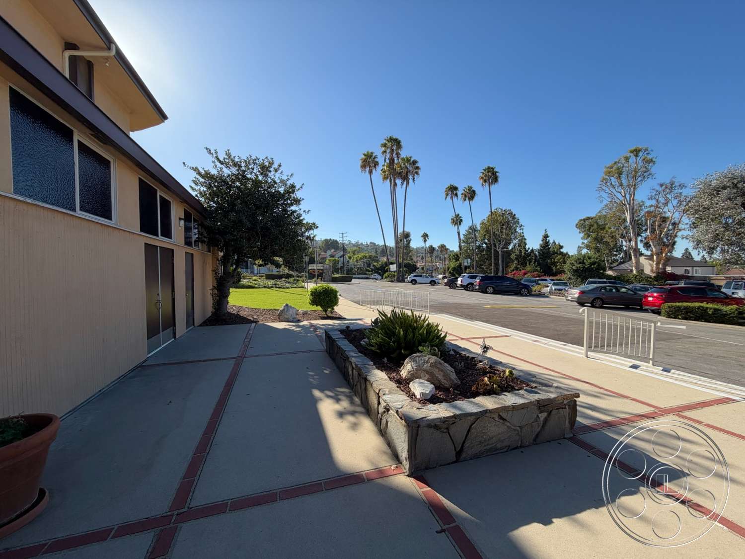 Community Center - exterior, glass windows, urban environment, concrete walkway, garden setting, flat roof design, modern architectural details, concrete patio floor, palm trees landscaping, brick inlay border, stone planter bed