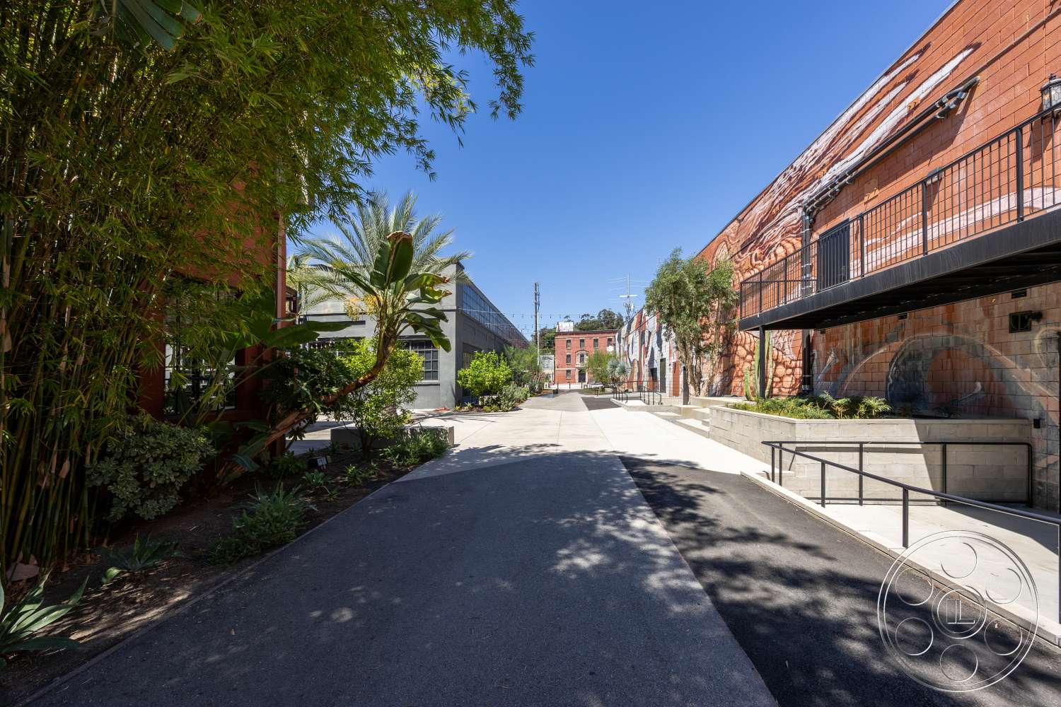 Club 74 - exterior, concrete walkway, tropical palm trees, bamboo privacy screen, brick building facade, concrete planter boxes, flat concrete surface, steel railing balcony, planted landscaping beds, painted mural wall
