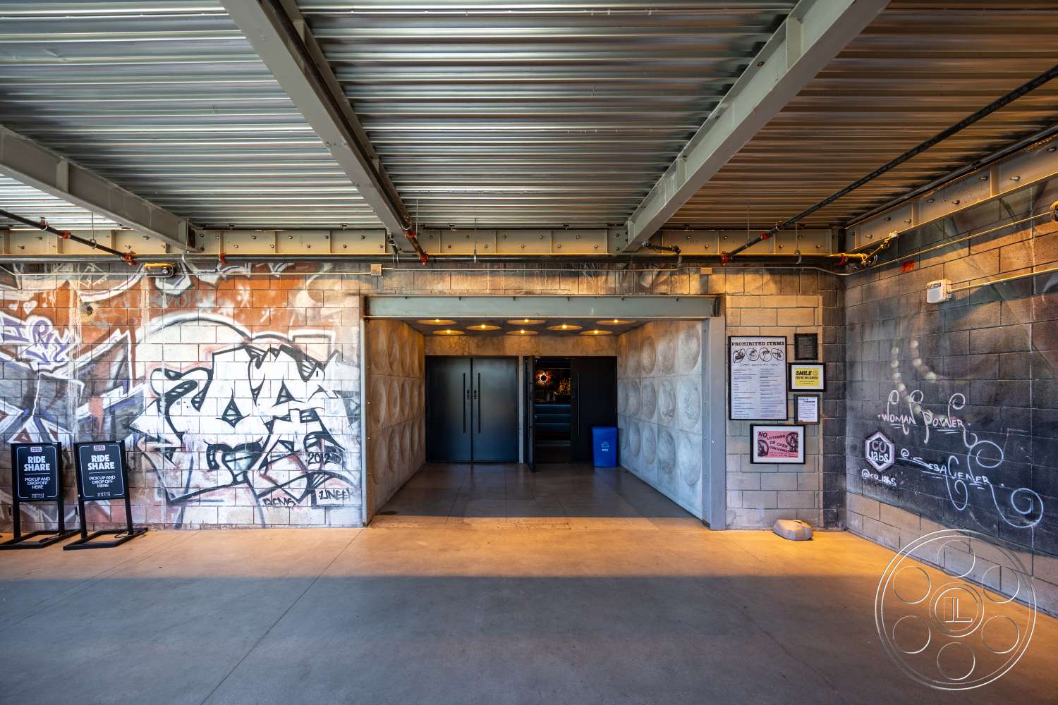 Club 74 - concrete flooring, exposed concrete walls, modern entrance, industrial style, urban setting, graffiti wall art, interior entrance hall, double glass doors, steel ceiling beams