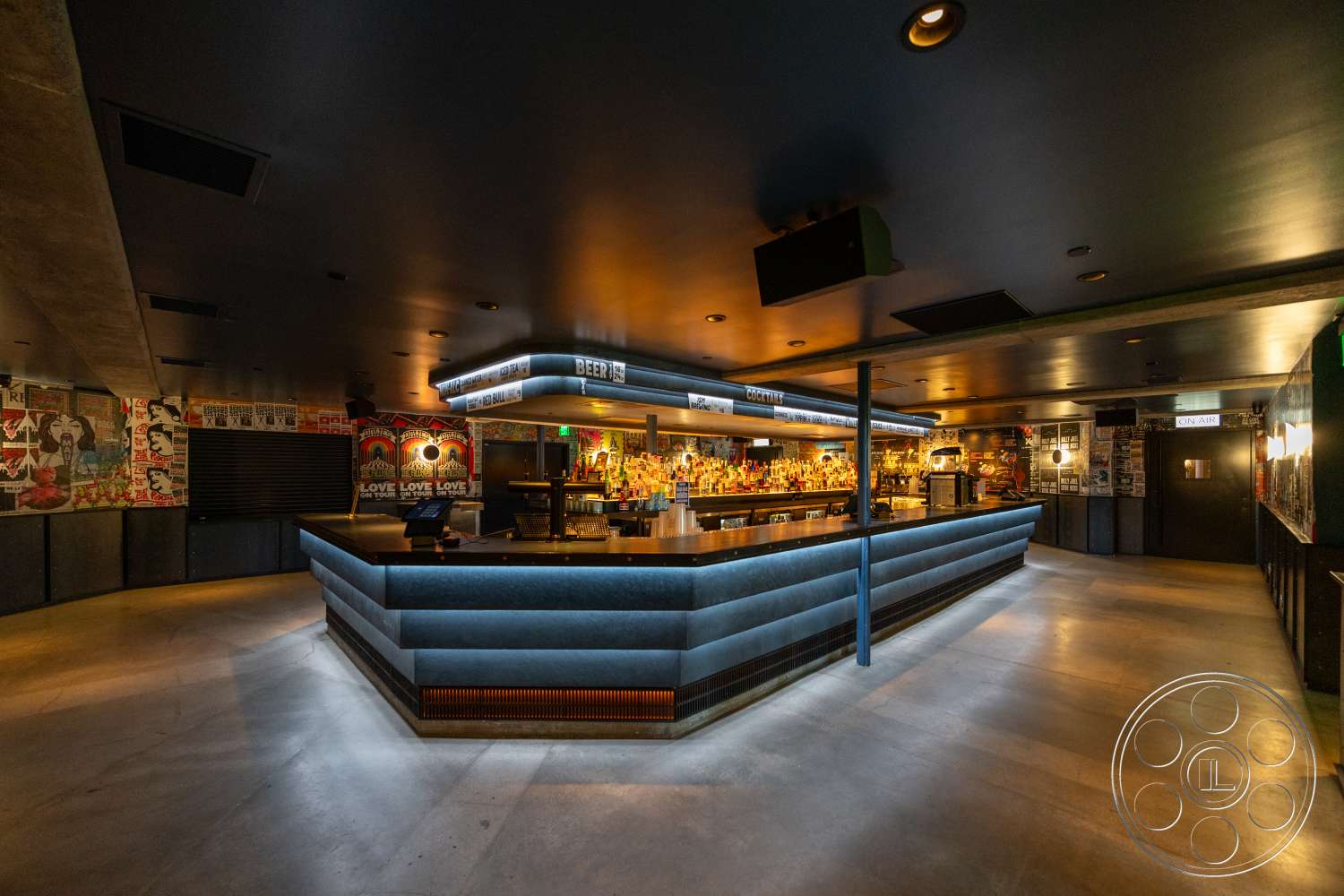 Club 74 - concrete flooring, open space layout, exposed concrete walls, track lighting, metal bar stools, modern industrial design, curved bar shape, dark painted ceiling, concrete bar top, LED backlit bar, graphic wallpaper accents
