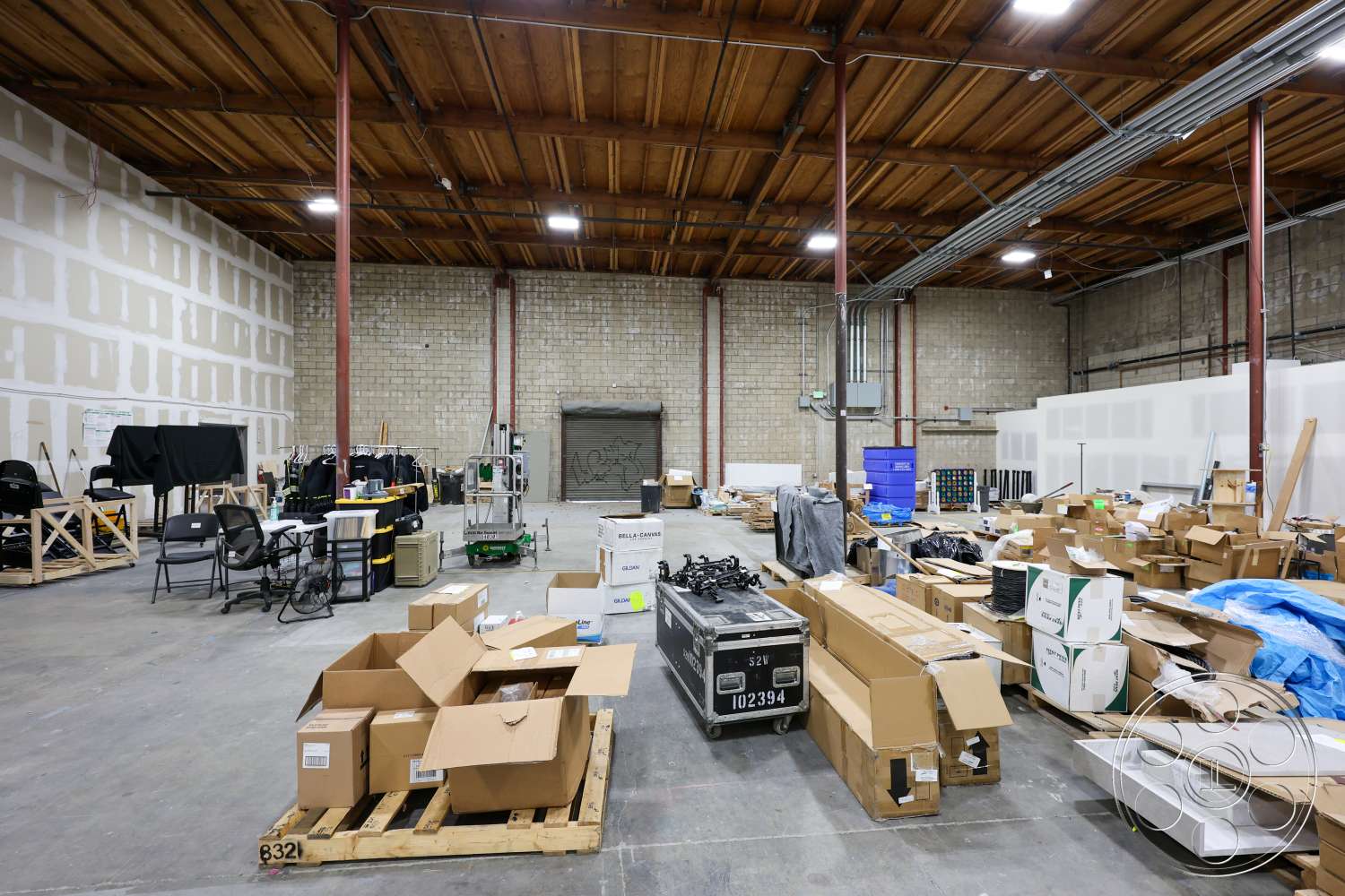 Club 74 - concrete floor, industrial lighting fixtures, exposed wood ceiling beams, metal support columns, block walls, open warehouse space, unfinished drywall, warehouse storage, reflective ceiling tiles