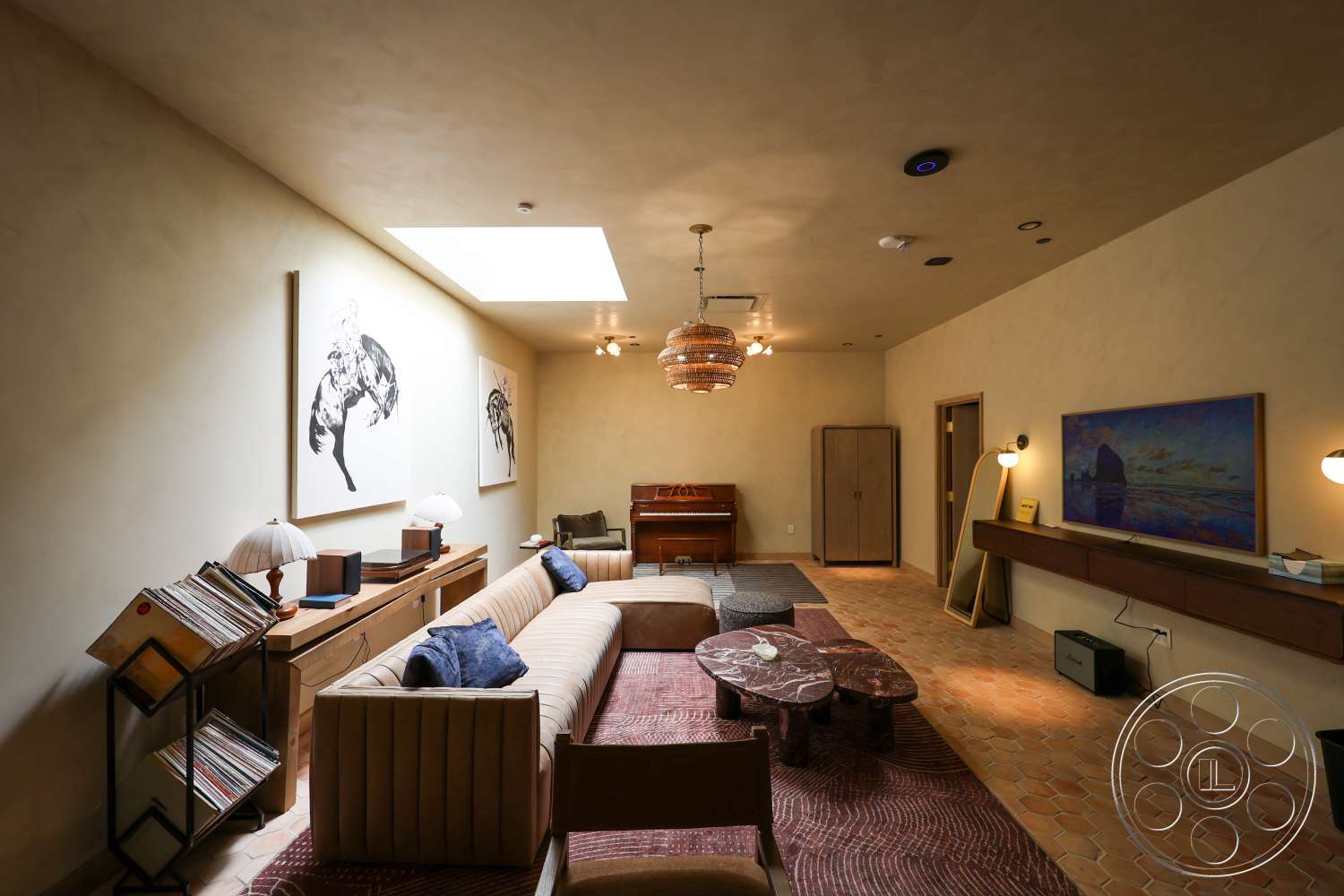 Club 74 - neutral color palette, textured plaster walls, rectangular coffee table, artwork wall decor, built-in wooden cabinetry, terrazzo tile flooring, exposed ceiling lighting, modern pendant chandelier, bent wood side table, plush sofa with vertical upholstery, rectangular skylight