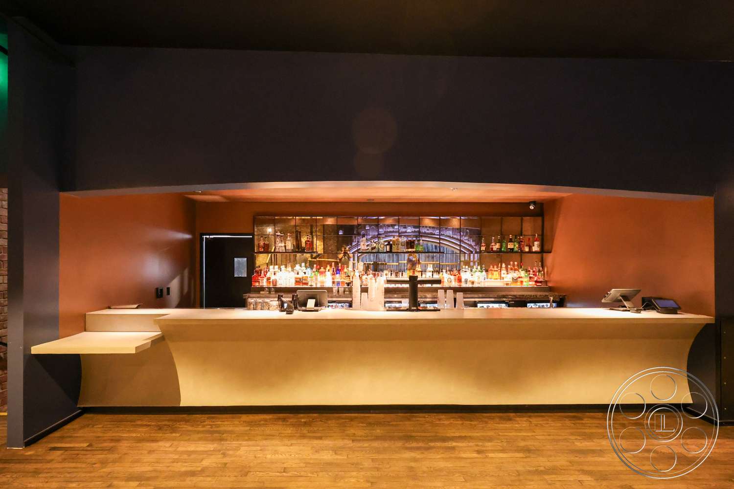 Club 74 - recessed lighting, exposed brick wall, textured plaster wall finish, high ceiling design, curved bar counter, wood plank flooring, dark wood bar cabinetry, glass shelf for bar display