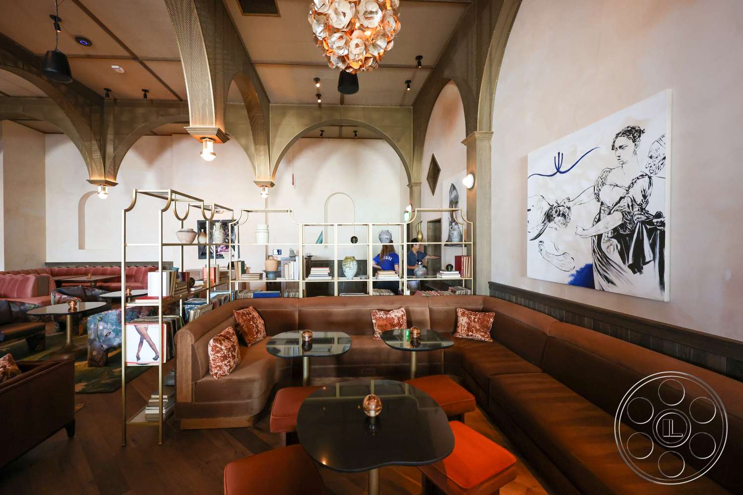 Club 74 - metal shelving unit, hardwood floor, textured wall treatment, decorative chandelier, open seating arrangement, plaster wall finish, gold metal accents, glass tabletop, arched ceiling details, softened seating area with velvet upholstery, upholstered booth seating, painted wall art, dim lighting features