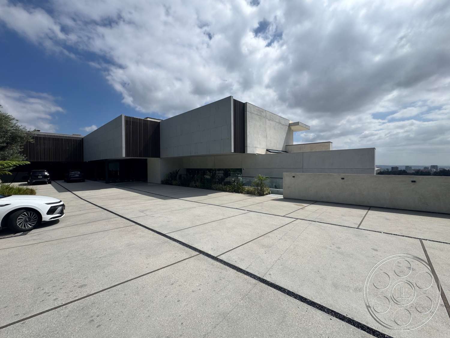 The Bellagio Estate - exterior, large glass windows, concrete walls, concrete driveway, outdoor parking area, flat roof design, landscaped garden area, modernist architectural style, rectangular concrete slabs, geometric architectural shapes, horizontal wood slat screening