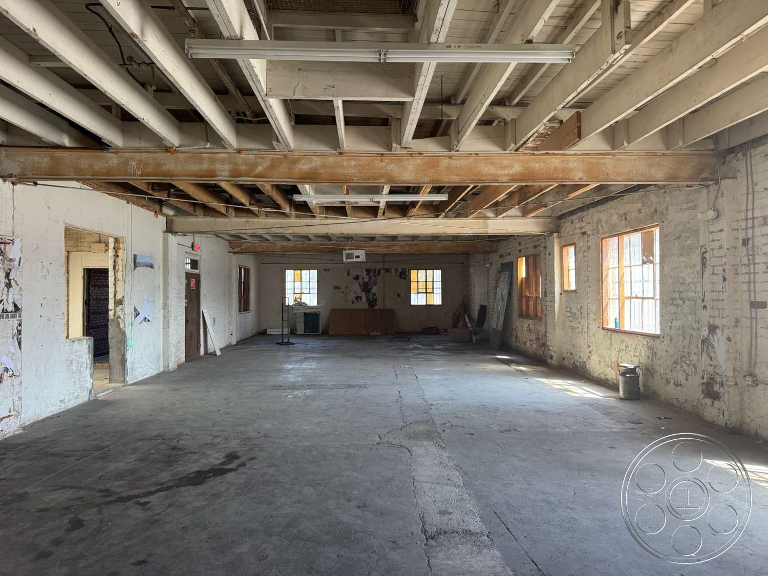 Warehouse 62 - natural light, concrete floor, industrial style, urban setting, unfinished space, exposed wooden ceiling beams, open interior layout, large windows with wooden frames, white painted brick walls