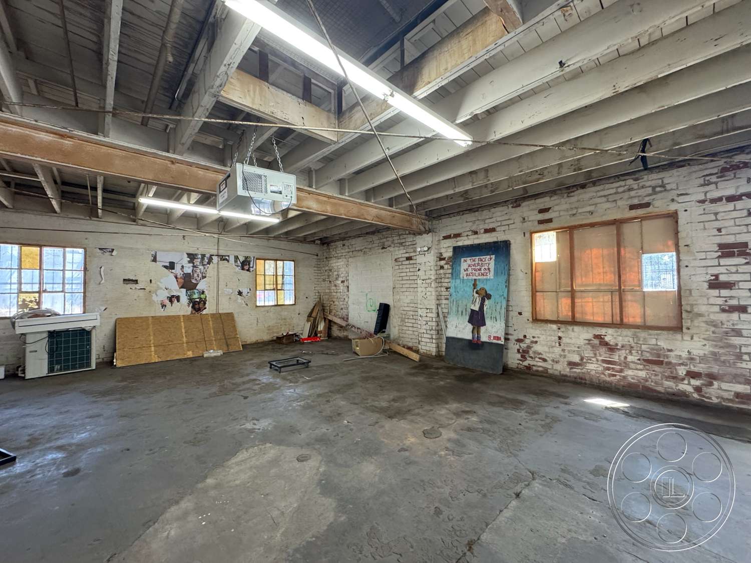 Warehouse 62 - large windows, open floor plan, concrete flooring, exposed brick walls, industrial lighting fixtures, exposed wood ceiling beams, urban warehouse interior
