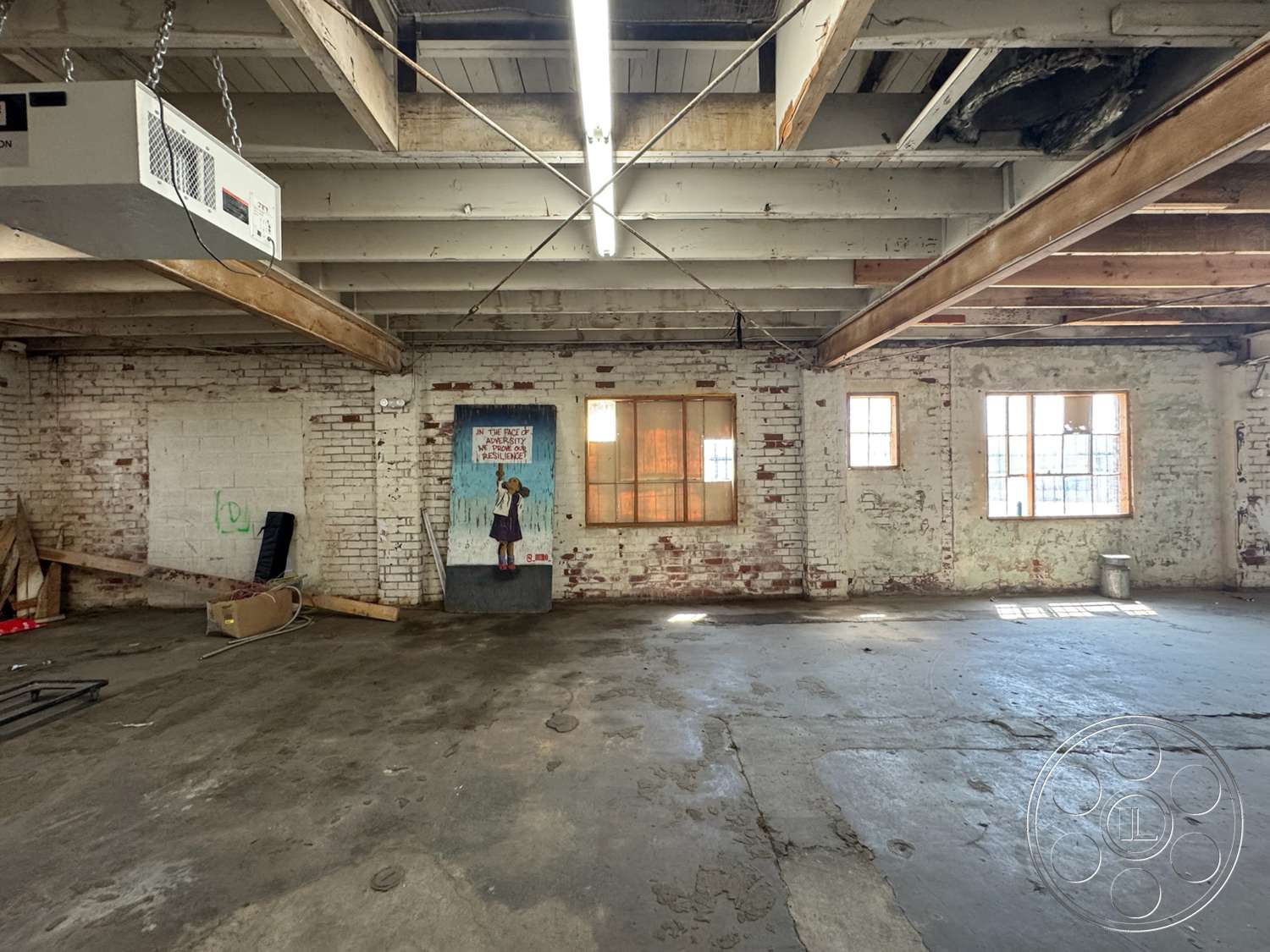 Warehouse 62 - exposed brick walls, large industrial windows, wood beam ceiling, raw concrete floor, open floor layout, industrial-style lighting, metal ceiling fixtures, unfinished drywall, painted brick accent wall
