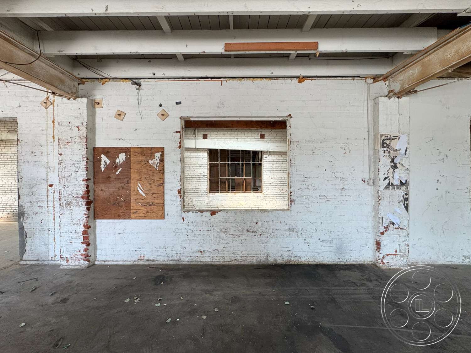 Warehouse 62 - open floor plan, concrete floor, interior space, exposed brick walls, wood ceiling beams, white painted brick walls, plywood wall paneling, industrial window with grid bars