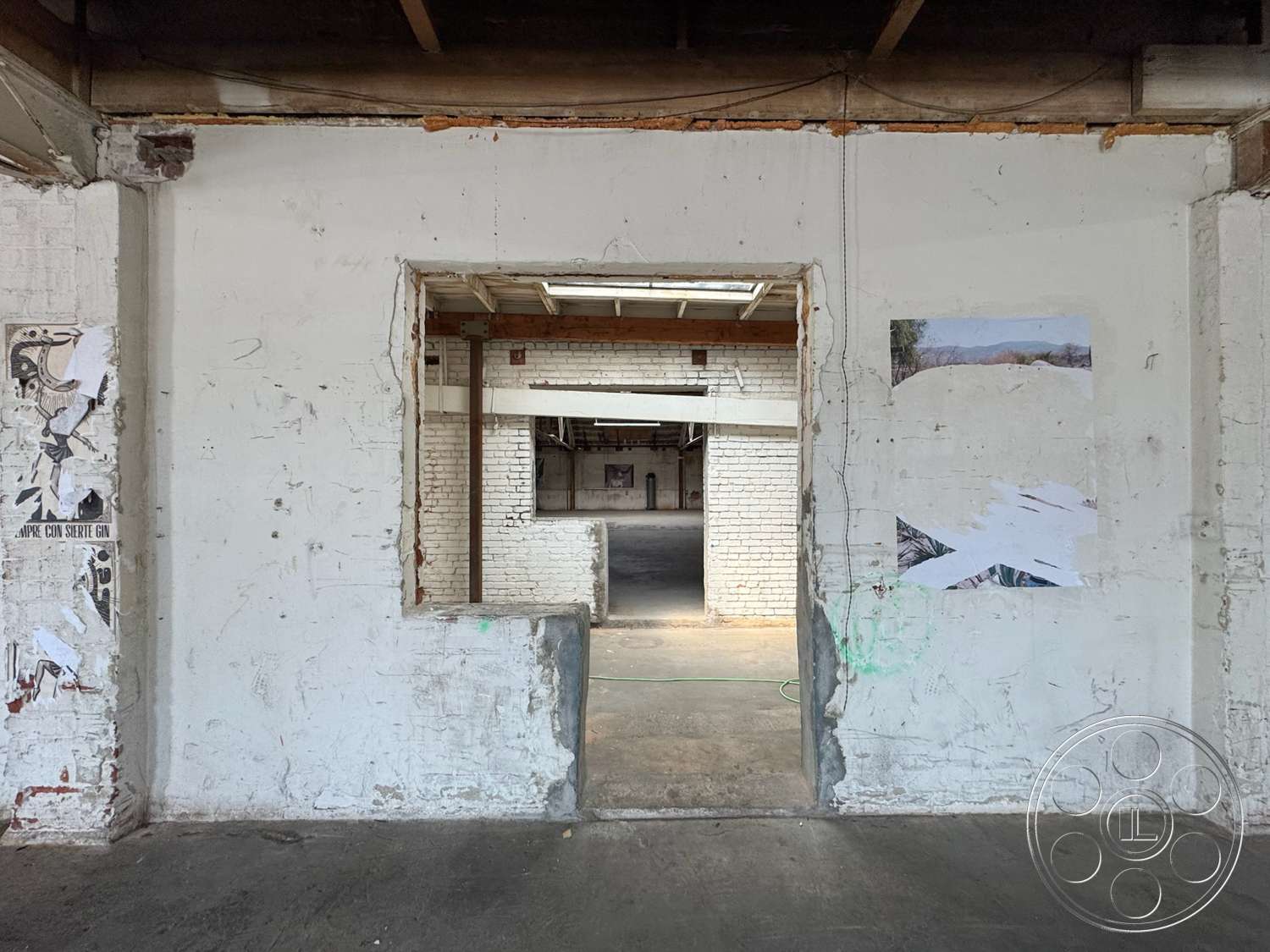 Warehouse 62 - minimalist design, open floor plan, concrete flooring, exposed brick walls, arched doorway, large openings, wood beam ceiling, urban interior, industrial style architecture, white painted interior walls