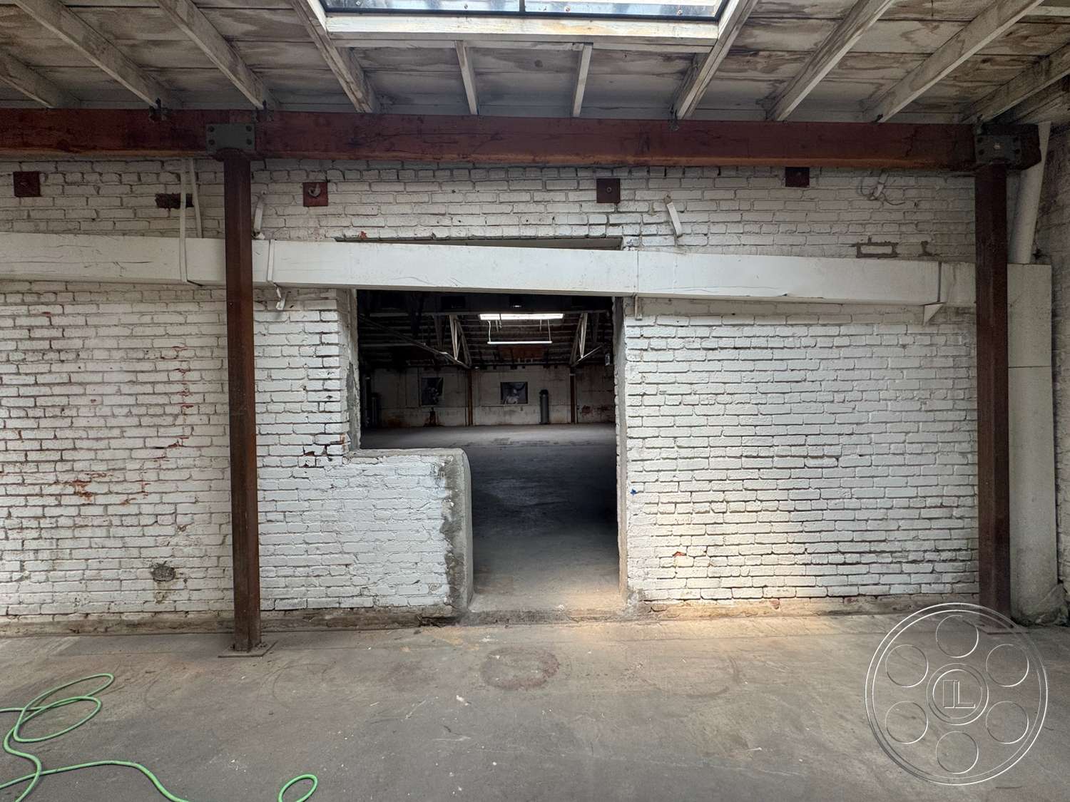 Warehouse 62 - open layout, concrete floor, exposed brick walls, wooden ceiling beams, steel support beams, industrial architectural style, natural lighting from skylights
