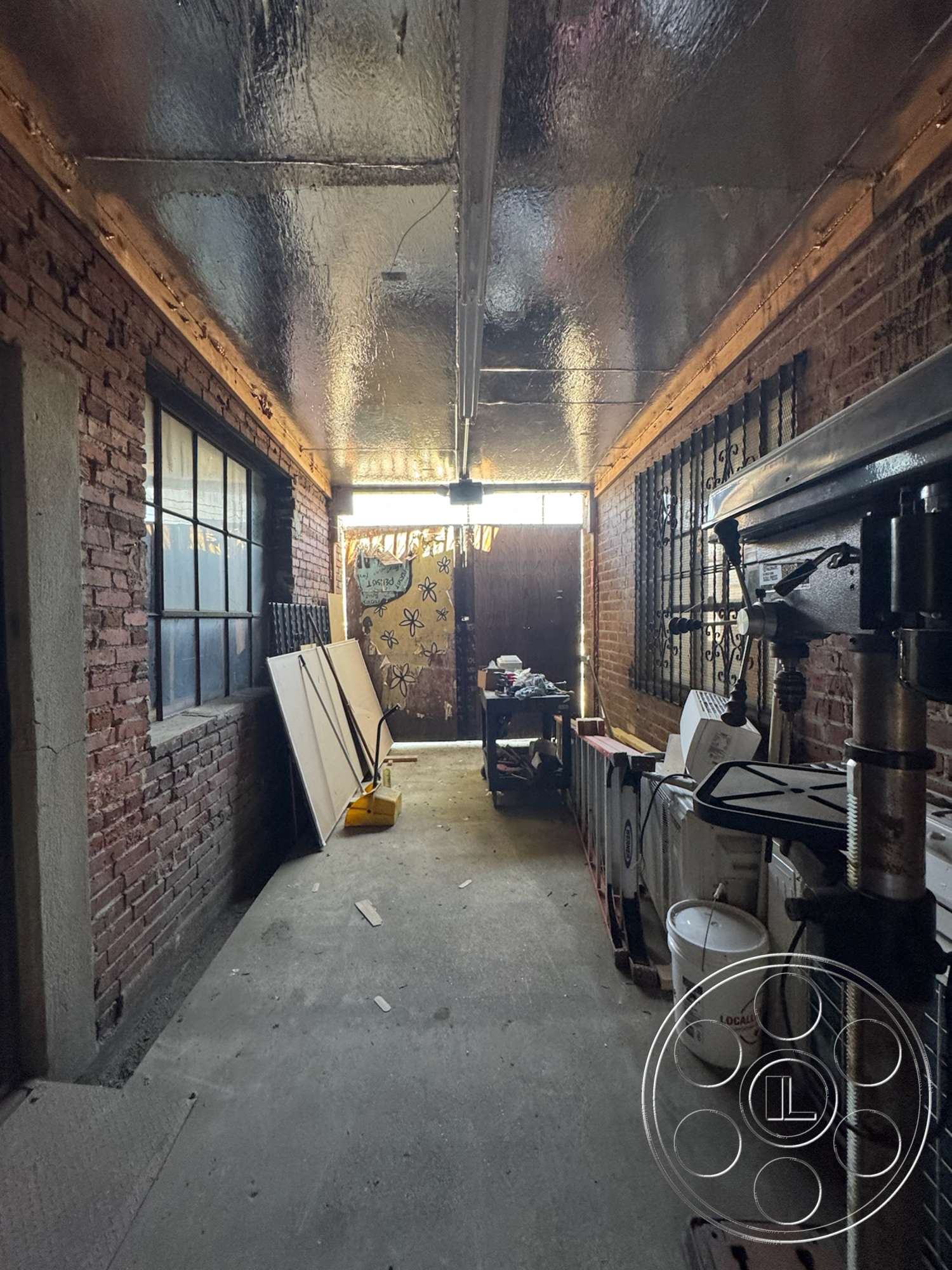 Warehouse 62 - large windows, concrete floor, exposed brick walls, suspended lighting fixtures, workspace area, urban environment, storage shelving, metal ceiling, interior hallway, rectangular hallway, industrial interior, wooden frames, painted wooden door