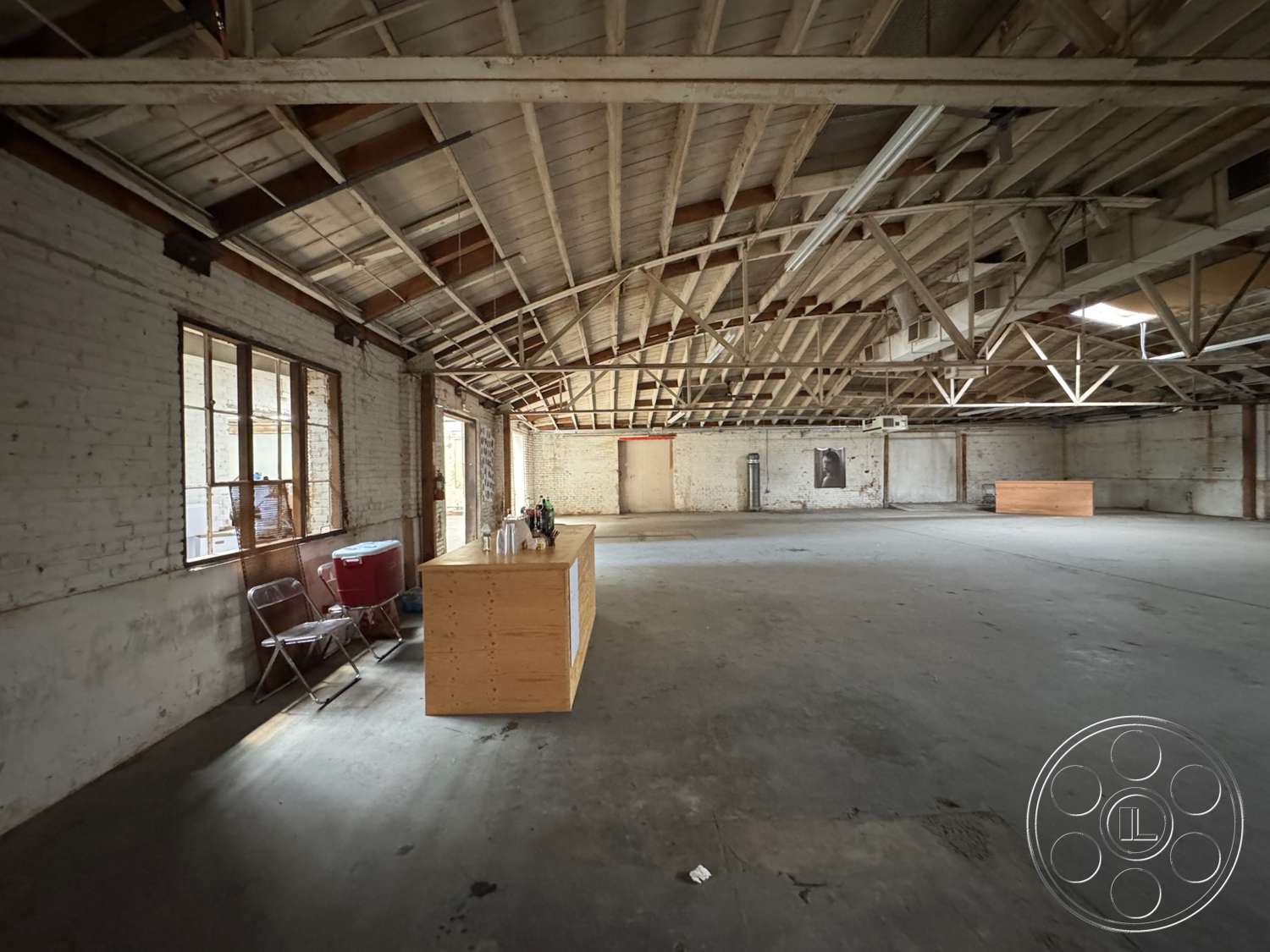 Warehouse 62 - natural light, open floor plan, concrete floor, exposed brick walls, wooden beam ceiling, large industrial windows, commercial space, minimalist interior, wooden counter island, rustic industrial style