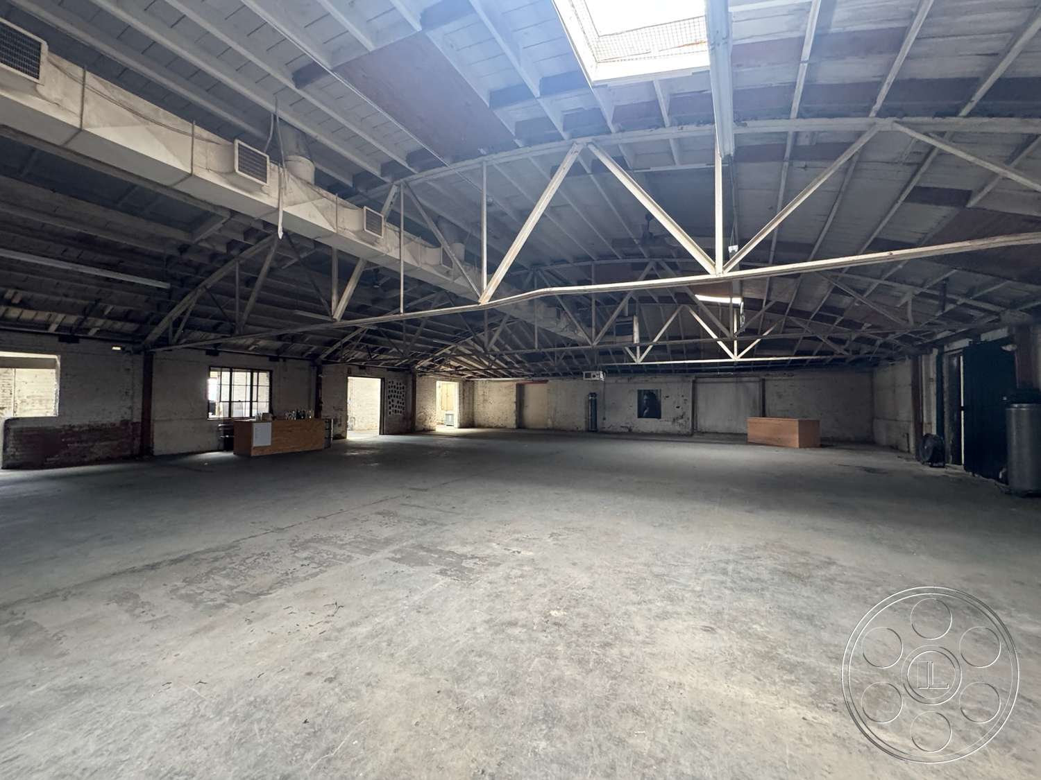 Warehouse 62 - natural light, open layout, concrete floor, brick wall, large industrial windows, skylight, exposed wood truss ceiling, raw industrial aesthetic, metal structural supports