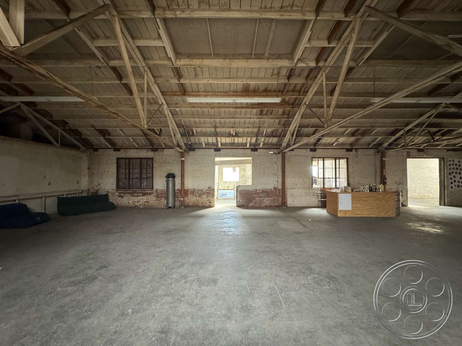 Warehouse 62 - natural light, open floor plan, concrete floor, brick wall accents, large rectangular windows, exposed wooden ceiling beams, industrial-style space
