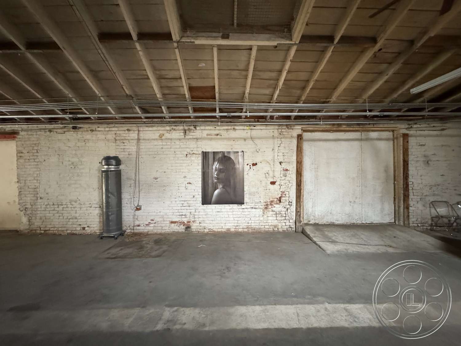 Warehouse 62 - minimalist design, concrete floor, exposed brick walls, wood ceiling beams, metal ductwork, photographic wall art, open layout space, industrial interior, painted white brick wall, large loading door