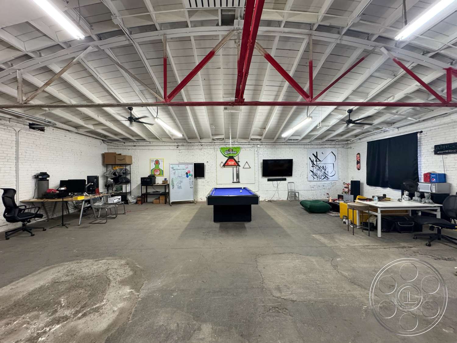 Warehouse 62 - open floor plan, concrete floor, exposed brick walls, industrial lighting fixtures, workspace area, entertainment area, pool table, television wall mount, wood beam ceiling, modern office furniture, blackout curtains, red metal trusses, creative mural art