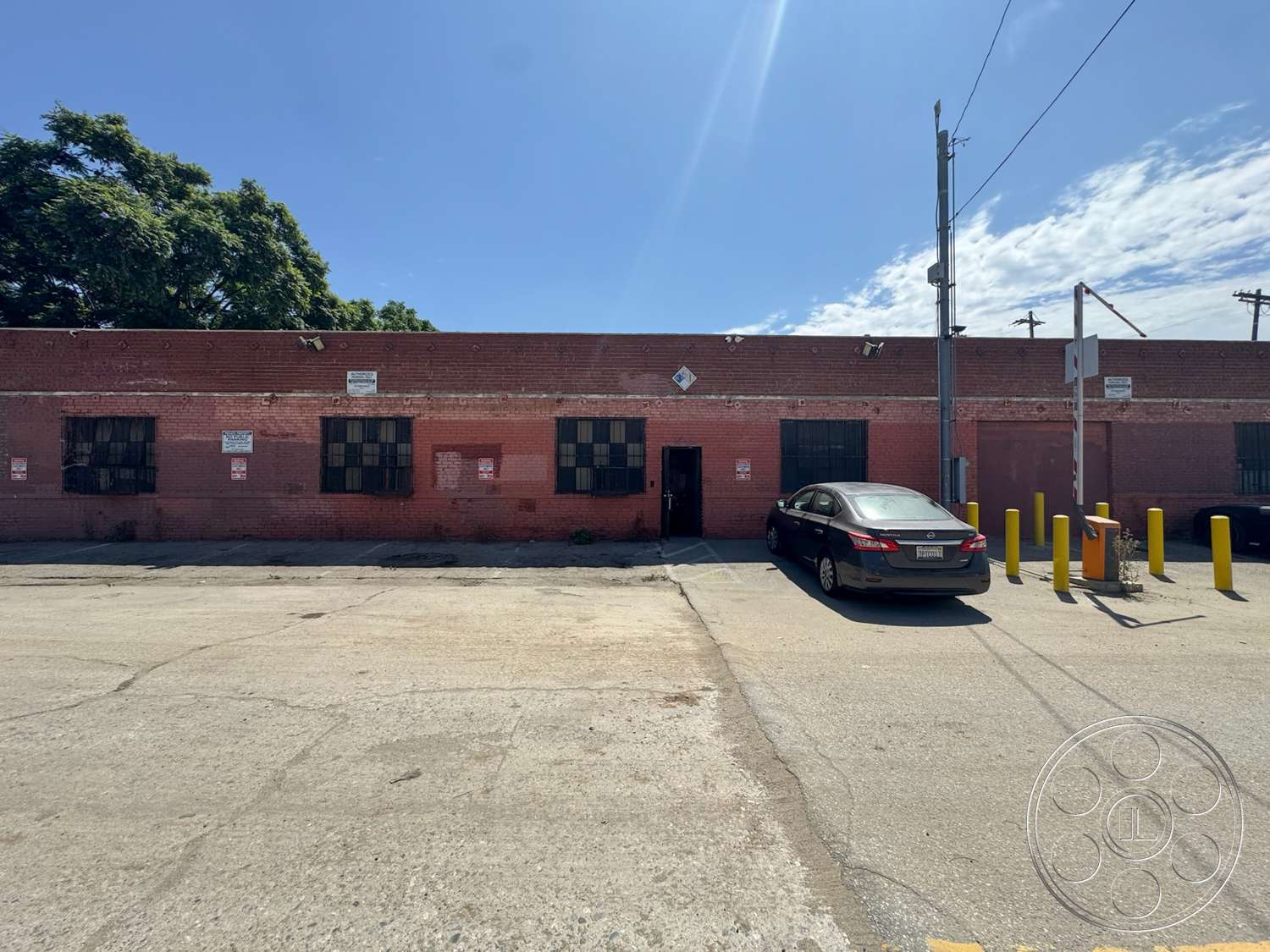 Warehouse 62 - exterior, industrial style, urban setting, red brick facade, flat roof structure, concrete parking area, brick warehouse building, metal barred windows, yellow parking bollards