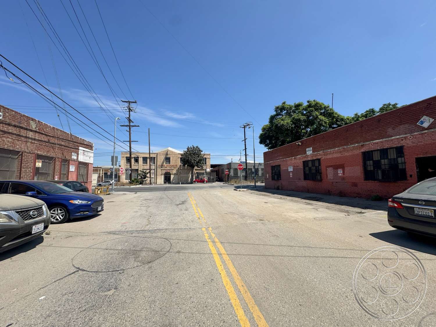 Warehouse 62 - exterior, concrete pavement, industrial architecture, clear blue sky, two-story building, telephone poles, urban street setting, asphalt roadway, red brick building facade, windows with black metal grilles