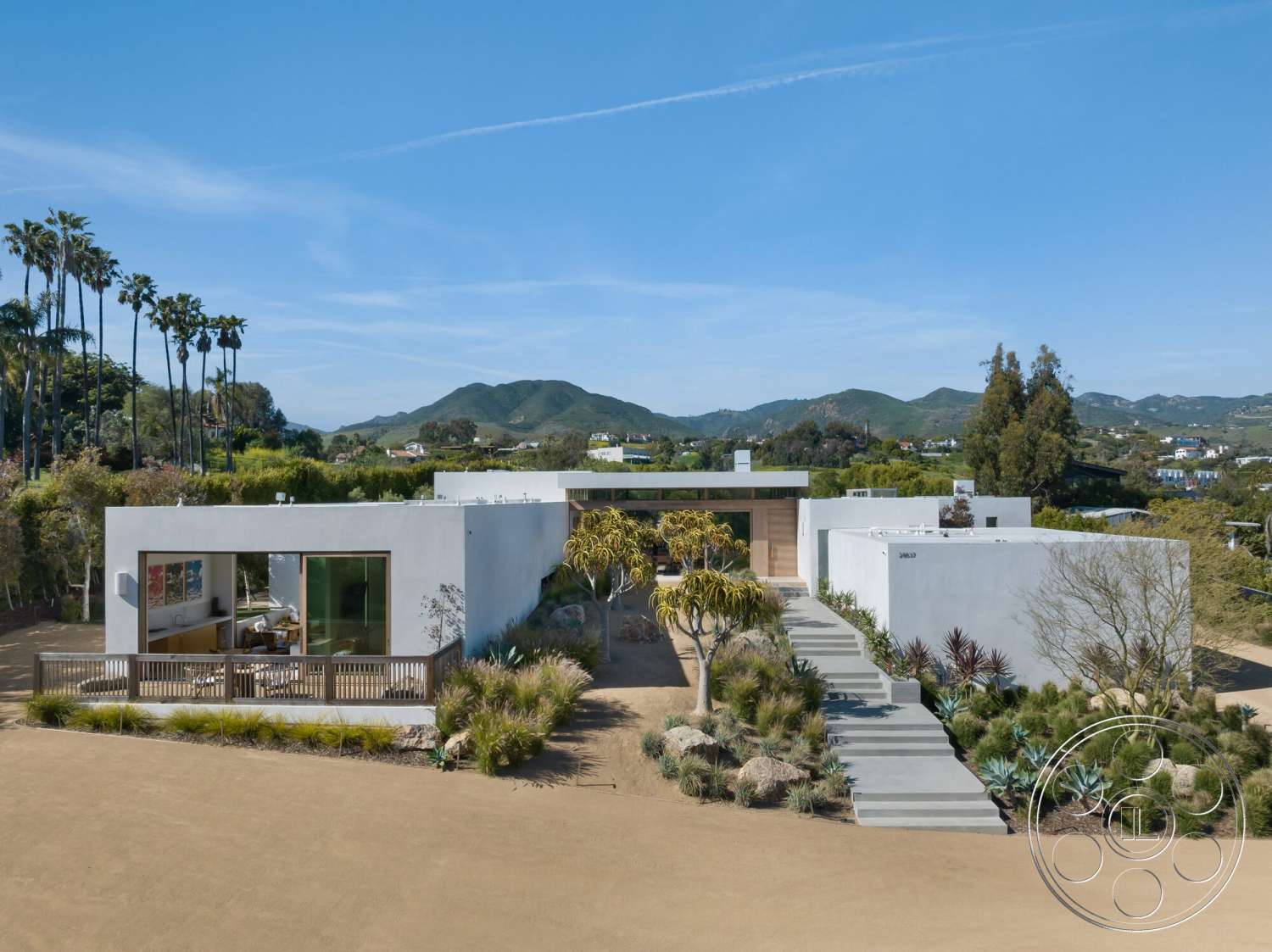 Modern 529 - exterior, outdoor living space, concrete walkway, flat roof design, landscaped garden area, stucco exterior walls, natural light through large windows, minimalist architectural style, two-story residence, palm tree accents, desert plants landscaping, panoramic mountain view, horizontal wood slat siding, smooth concrete patio surface, decorative wood entrance feature