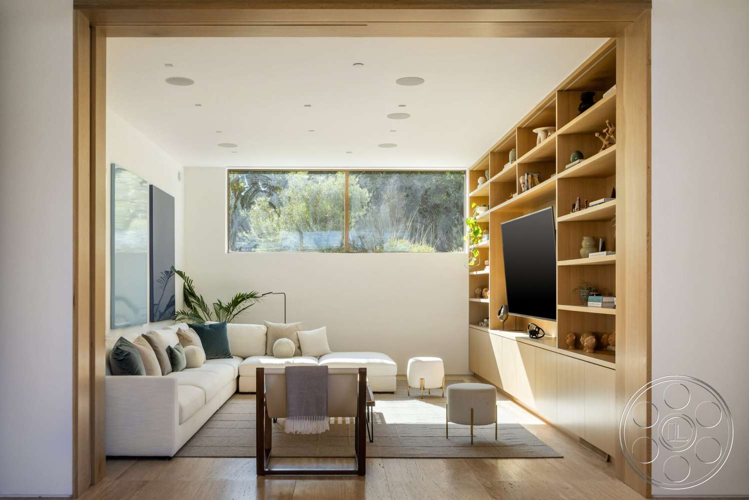 Modern 529 - textured area rug, light hardwood flooring, open concept living room, large floor-to-ceiling windows, natural light-filled space, white painted walls, contemporary decor elements, custom built-in wooden shelving, minimalist sofa with throw pillows