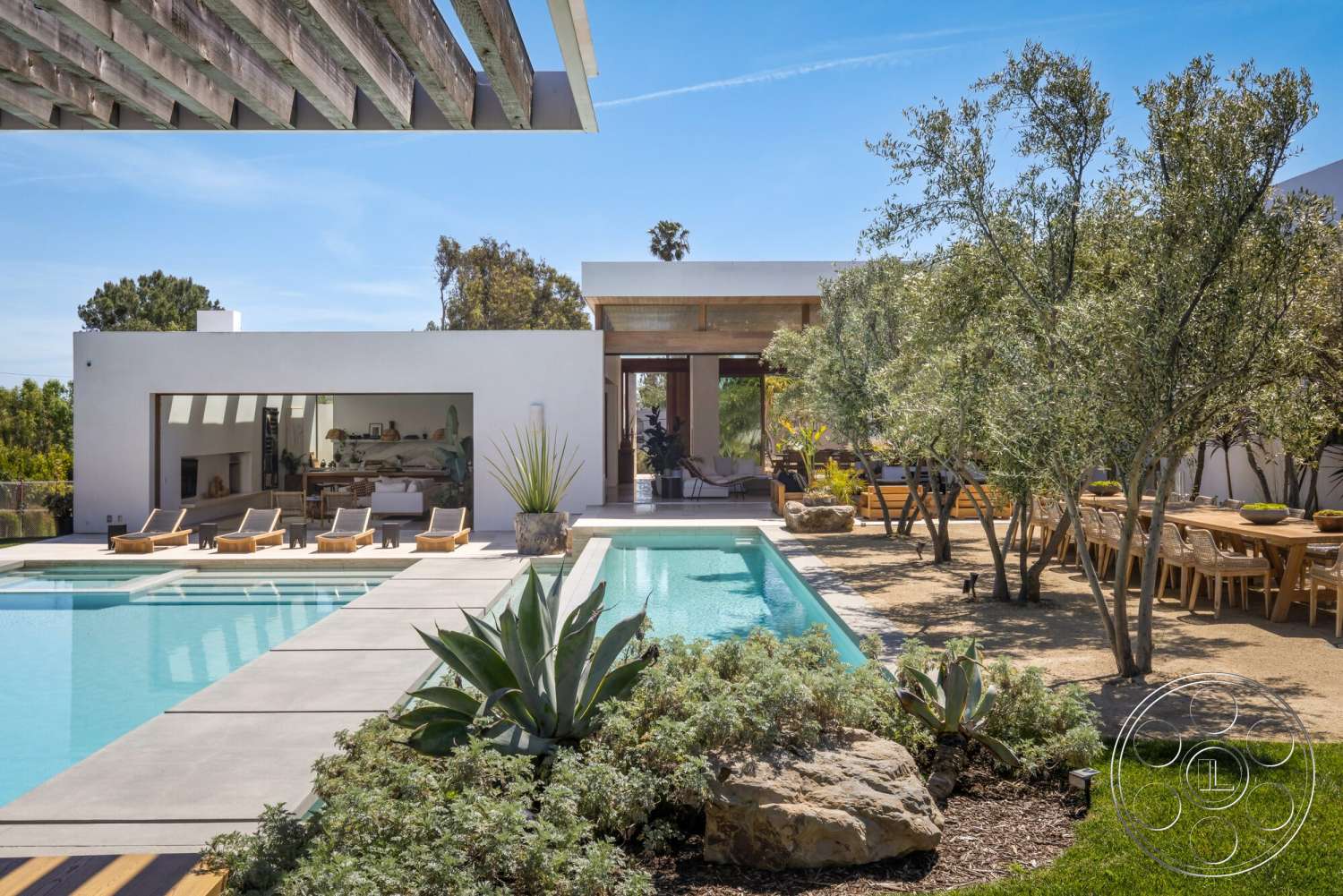 Modern 529 - exterior, flat roof, outdoor seating area, rectangular swimming pool, floor-to-ceiling windows, sliding glass door, modern architectural style, light-colored stucco walls, wooden pergola, suburban backyard, concrete patio flooring, landscape rock features, concrete swimming pool deck, planted succulents, hardwood outdoor dining table