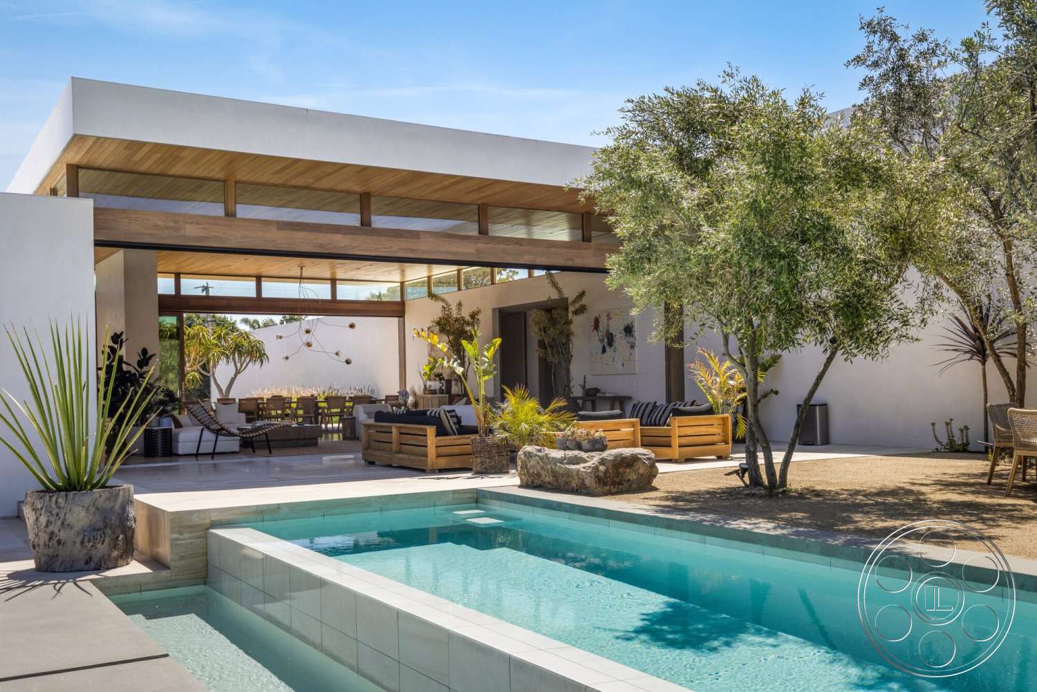 Modern 529 - exterior, sliding glass doors, modern architectural style, rectangular pool, wood ceiling beams, wooden outdoor furniture, sunny outdoor setting, concrete patio flooring, concrete pool border, open-air dining area, lush greenery landscaping, stone outdoor planters