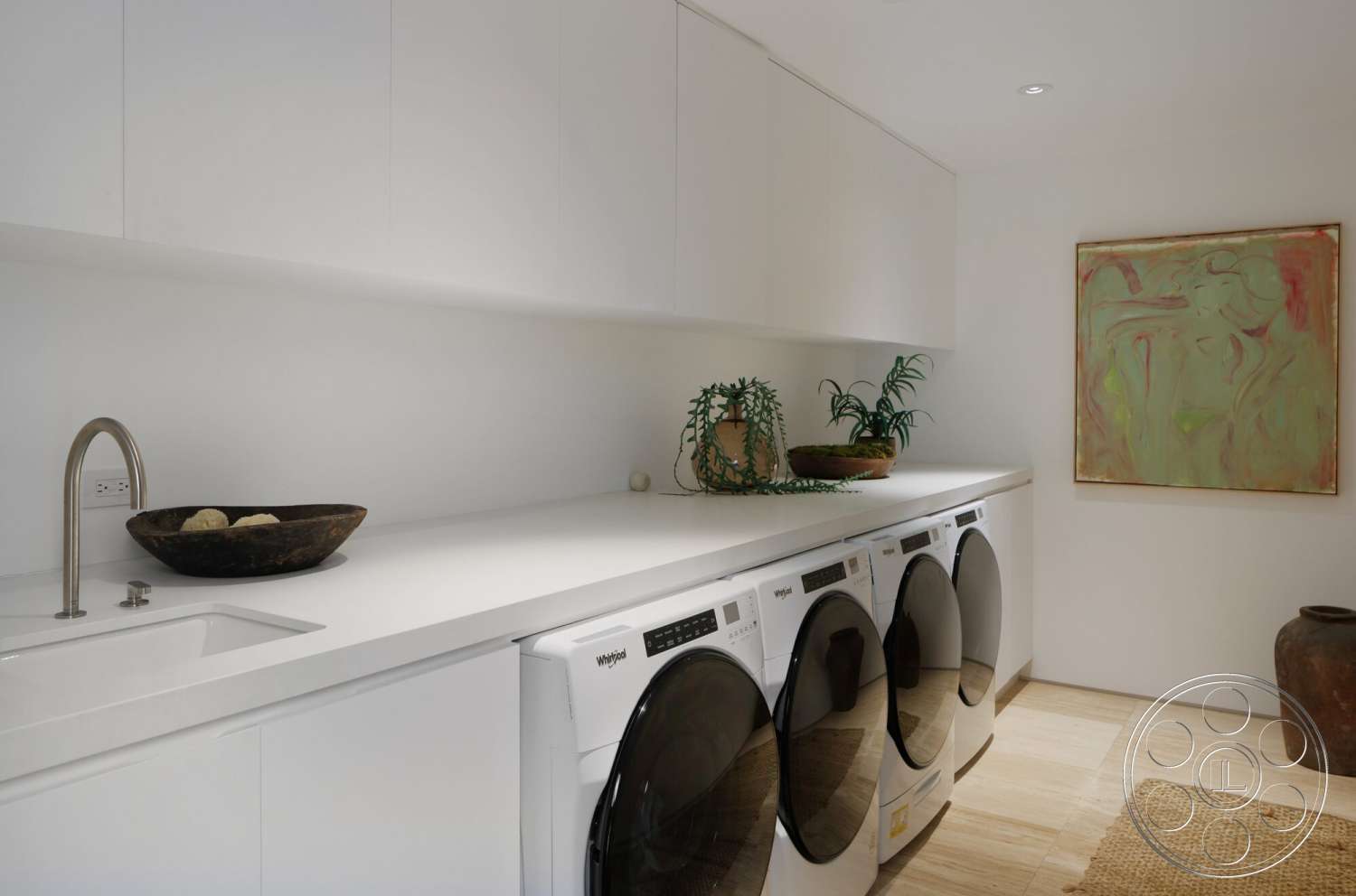 Modern 529 - minimalist decor, light wood flooring, plant accents, white painted walls, stainless steel faucet, washer and dryer units, artwork wall feature, solid surface countertop, modern laundry room design