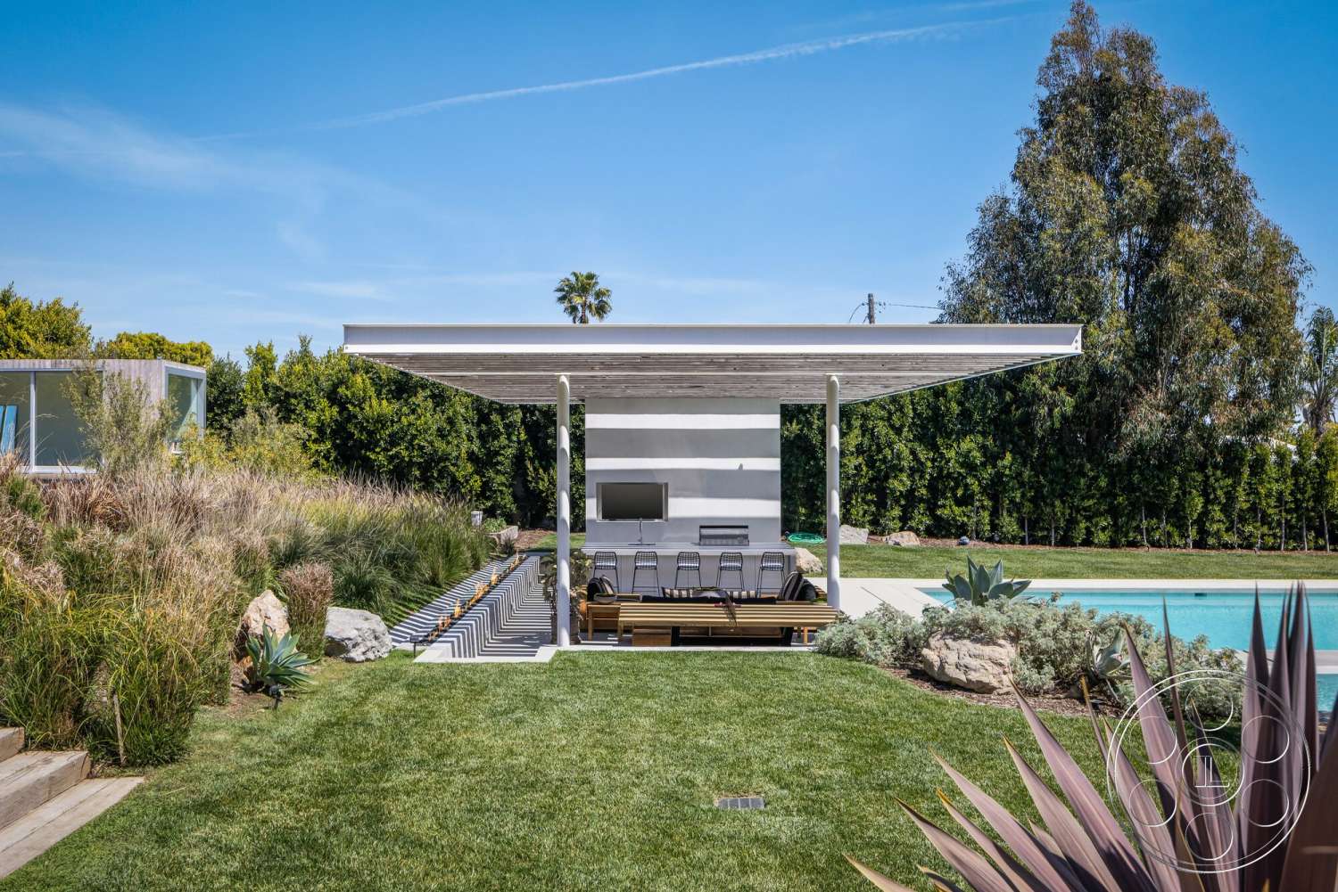 Modern 529 - exterior, rectangular swimming pool, contemporary architecture, concrete pool deck, wood pergola structure, modern outdoor seating area, lush landscaping with succulents, synthetic grass lawn, linear stone pathway, horizontal wood slats roof, tall green privacy hedges