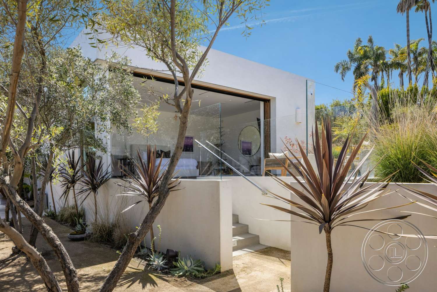 Modern 529 - exterior, landscaped garden, white stucco walls, modern design, glass railing, concrete steps, clear blue sky, steps leading to entrance, minimalist architectural style, rectangular entrance, tropical plant landscaping, broad sliding glass doors