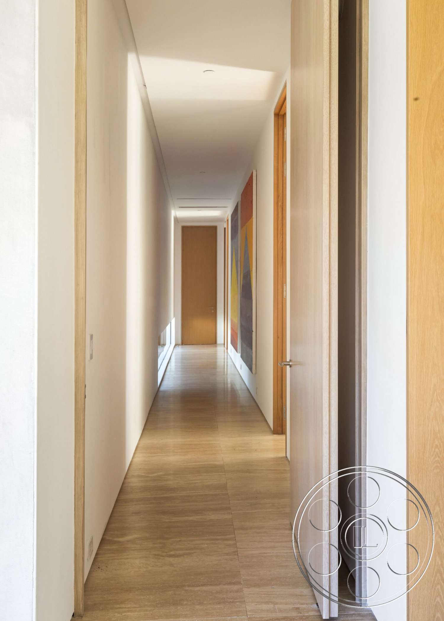 Modern 529 - minimalist design, artwork on walls, floor-to-ceiling windows, light-colored tile flooring, natural wood trim, interior hallway, natural light illumination, white painted walls, wood panel interior doors, long narrow hallway