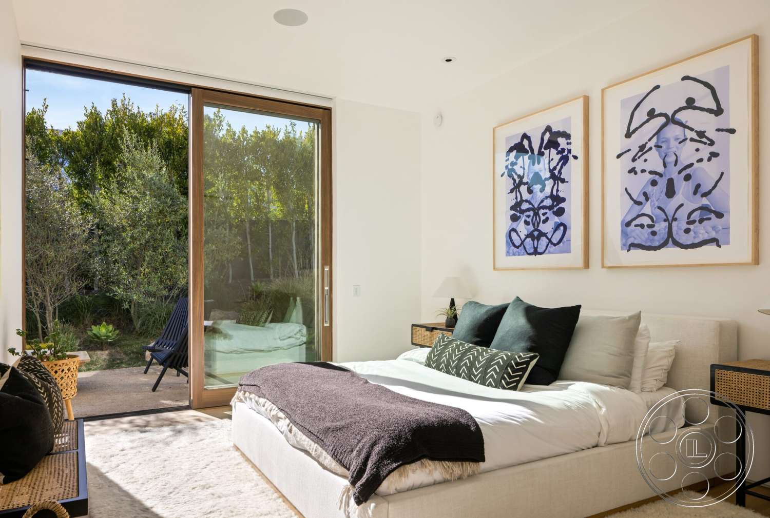 Modern 529 - minimalist decor, plant accents, floor-to-ceiling windows, soft area rug, light gray bedding, black and white abstract wall art, wood frame windows, modern lounge chair, textured white wall, light hardwood bedroom floors, dark throw blanket, queen-size bed with decorative pillows, woven basket side tables, patio access door
