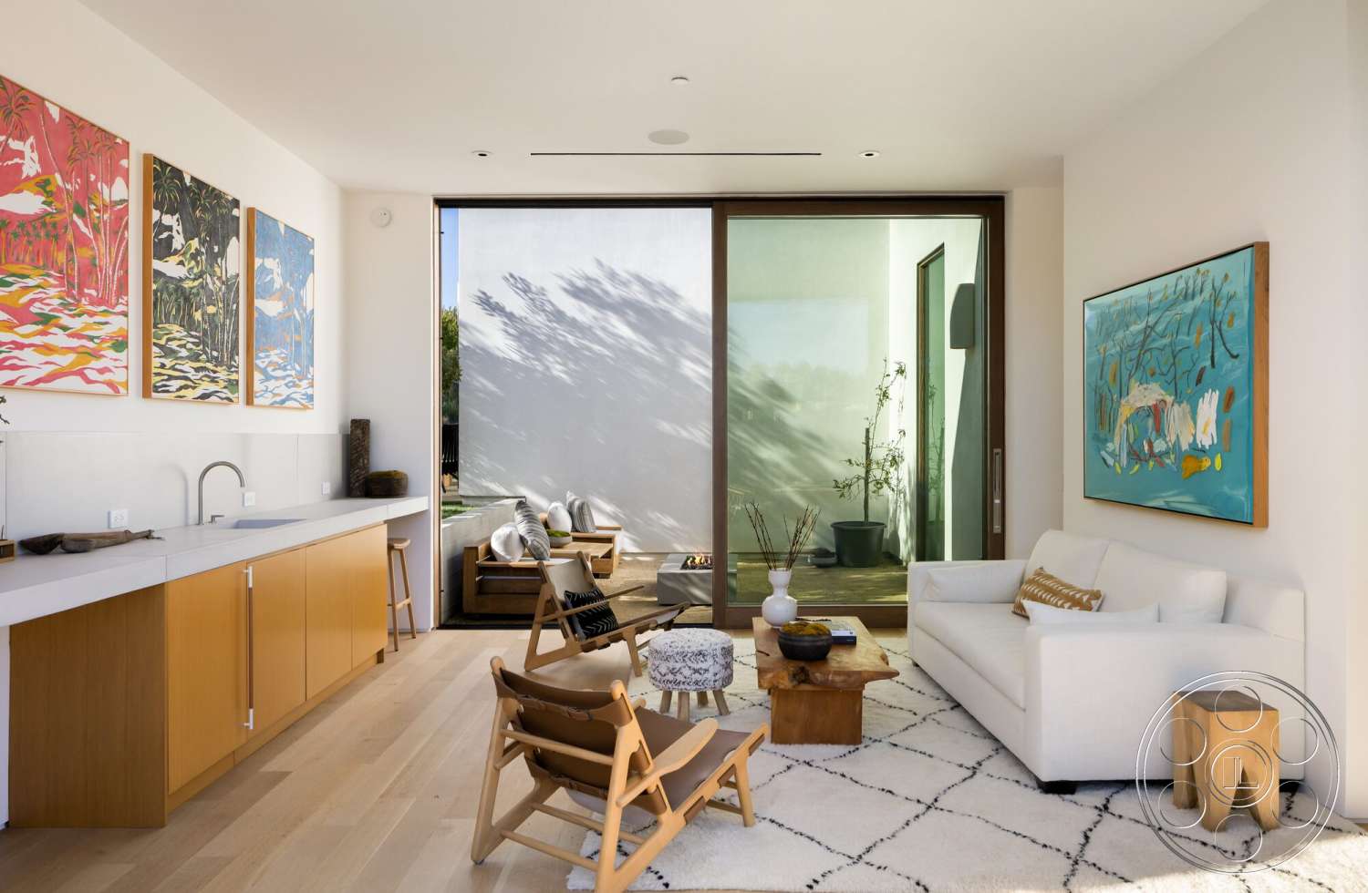 Modern 529 - indoor plants, textured area rug, wooden chairs, modern kitchen cabinetry, white painted walls, open concept living area, floor-to-ceiling glass sliding doors, light wood plank flooring, laminate kitchen countertops, framed art pieces on walls, wooden accent coffee table, minimalist sofa