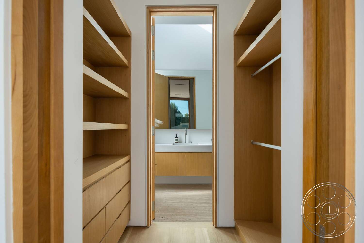 Modern 529 - light wood cabinetry, white countertop, natural light from window, floor-to-ceiling mirror, clean lines architecture, modern bathroom vanity, open closet space, wood shelving units, shallow bathroom sink
