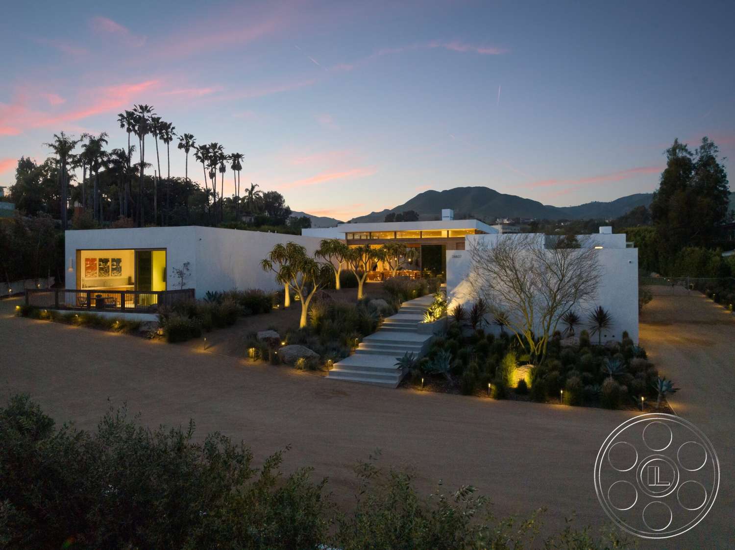 Modern 529 - exterior, palm trees, minimalist design elements, large glass windows, concrete pathway, modern architectural style, mountain view, desert landscaping, outdoor lighting features, stucco walls, gravel driveway, flat roof design, wooden entry deck